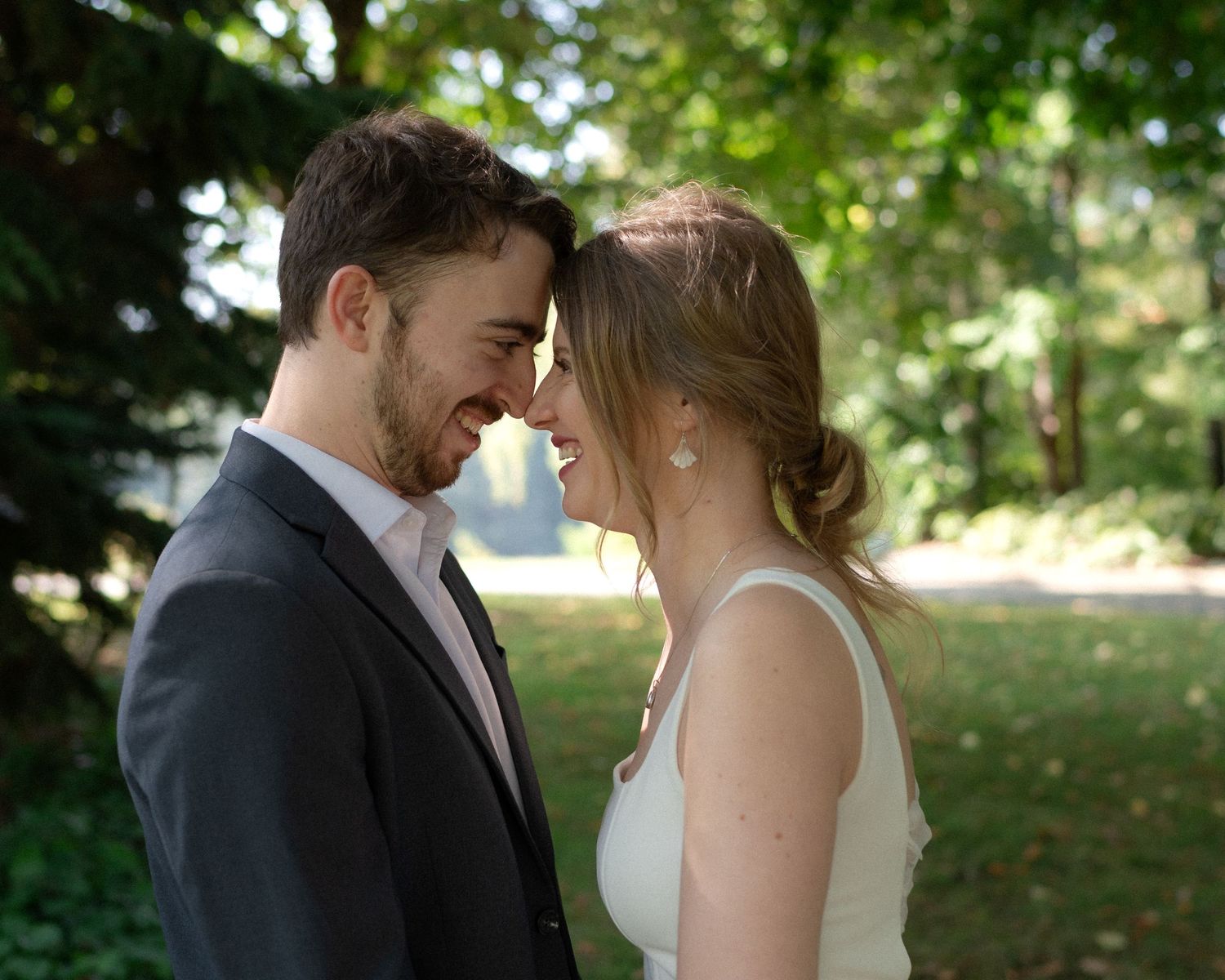 A tender moment between newlyweds sharing an intimate moment in a garden setting.