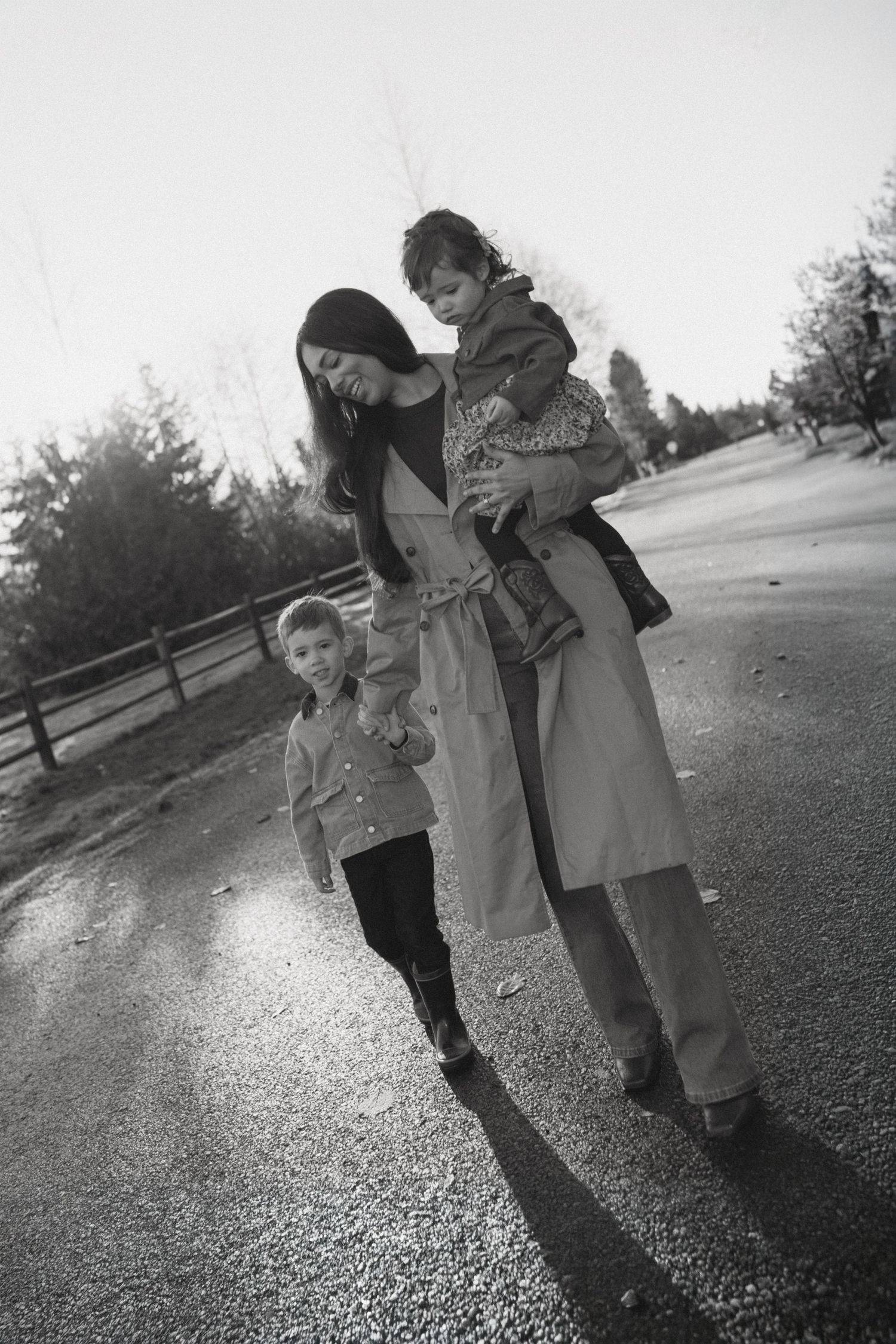 Three children play together outdoors in a black and white photo series showing them leaning and interacting.