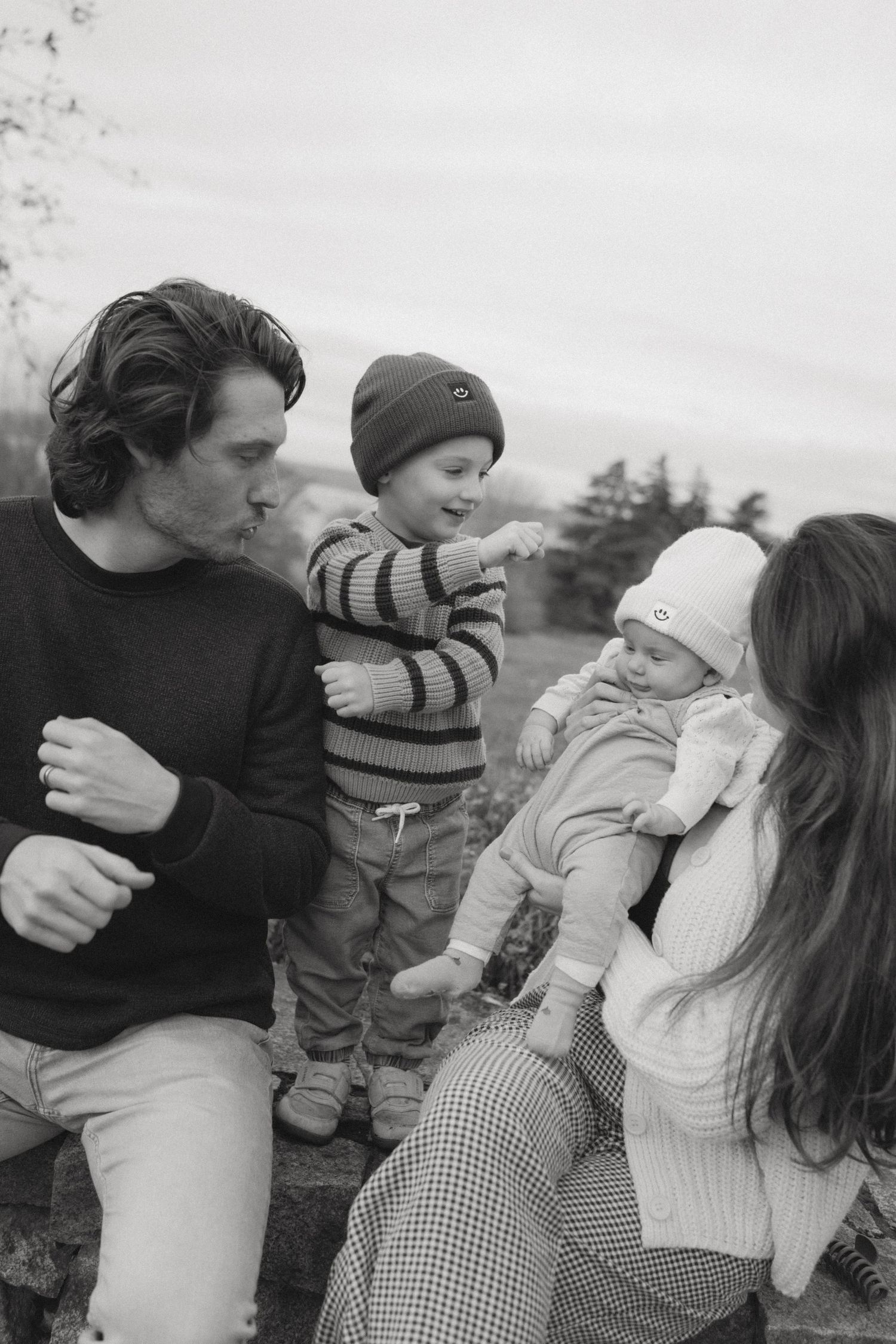 Black and white portrait of a family sharing tender moments outdoors.