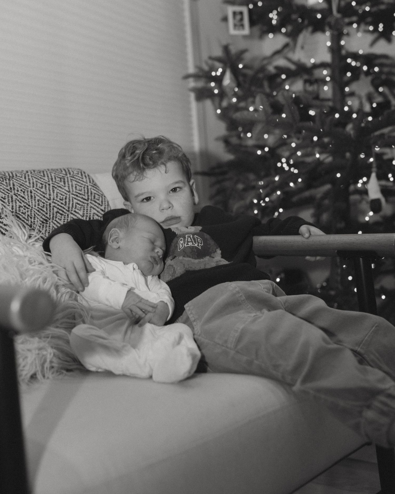 Black and white series of relaxing moments by a Christmas tree with twinkling lights.