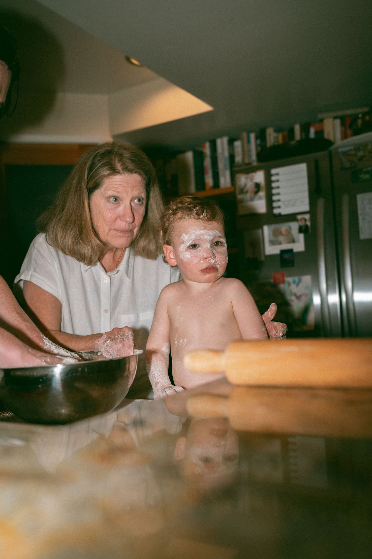 Adult and child lean over a wooden table surface in a sequence of similar candid shots in warm indoor lighting.