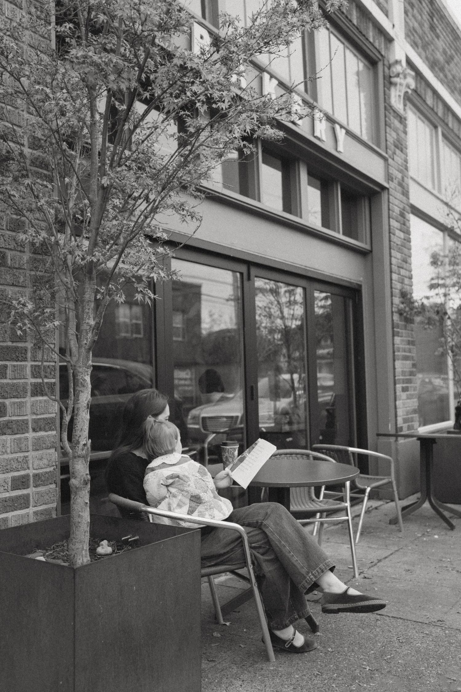 Black and white series showing quiet moments on benches outside a brick building.