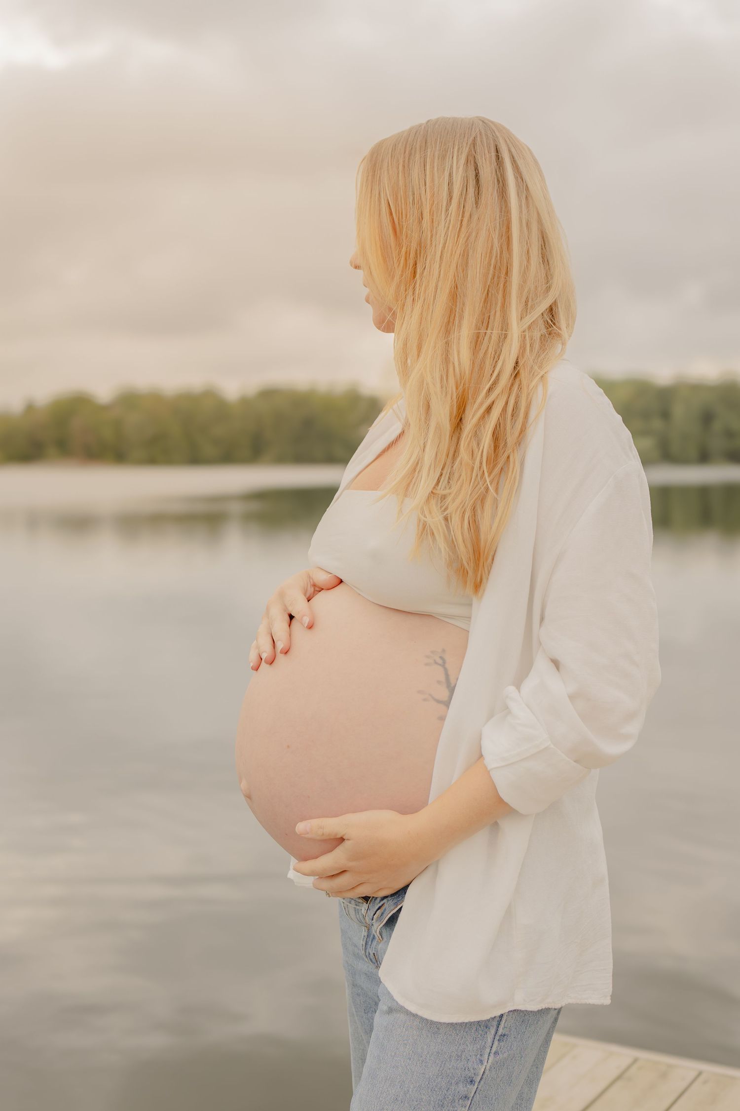 Gravid kvinna vid sjö under naturlig gravidfotografering i Stockholm, fotograferad av gravidfotograf.