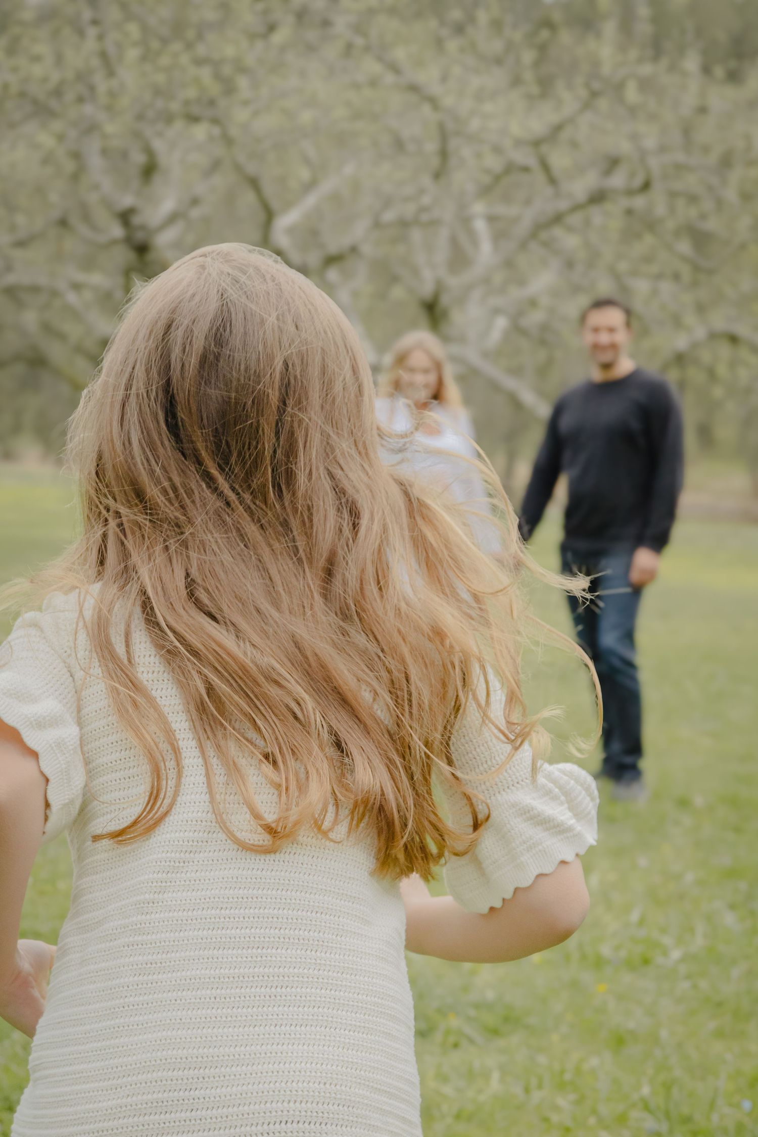 Barn springer mot sina föräldrar under en lekfull familjefotografering utomhus i Stockholm.