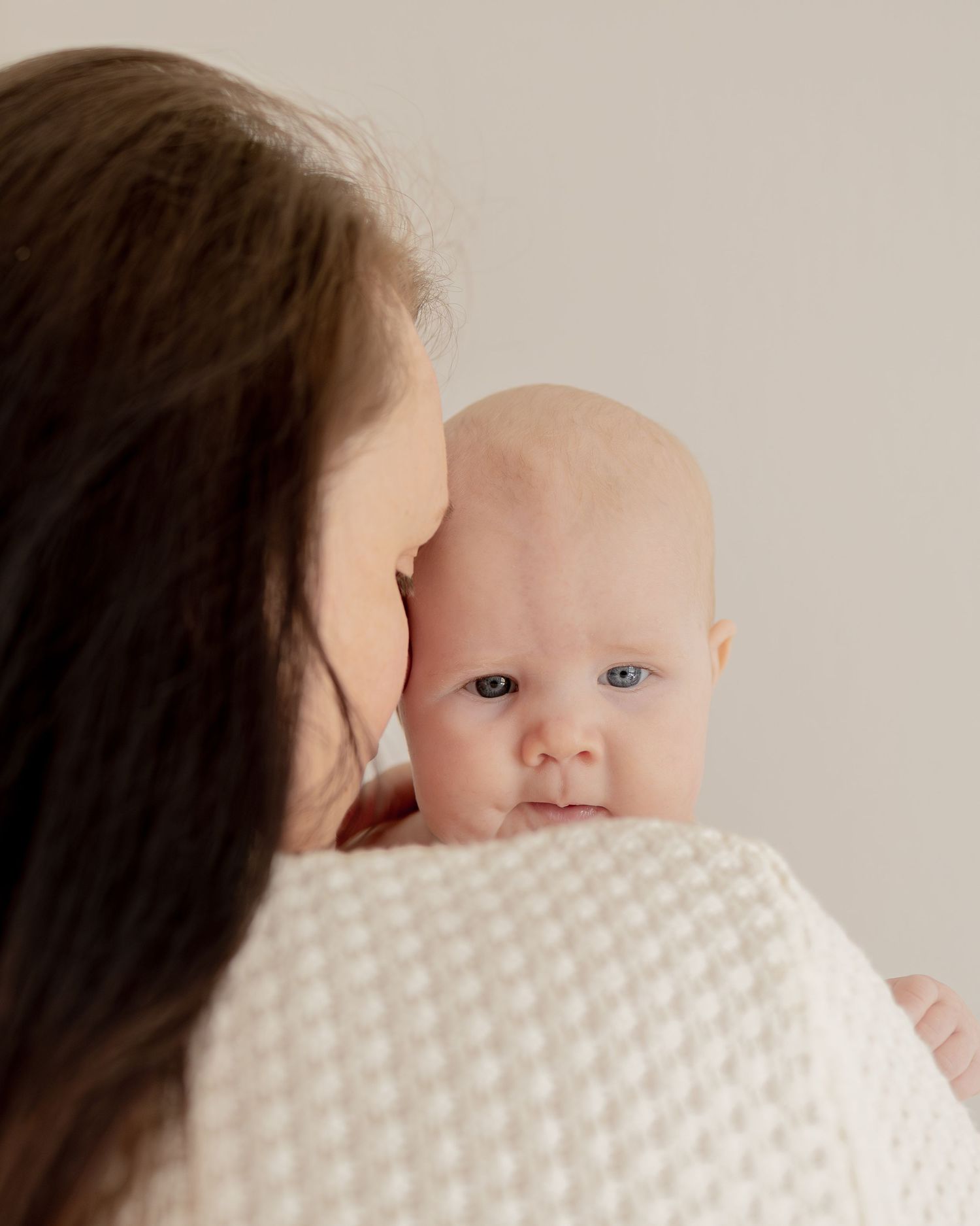 Nyföddfotografering i naturligt ljus med närbilder på öm närhet mellan mor och bebis.