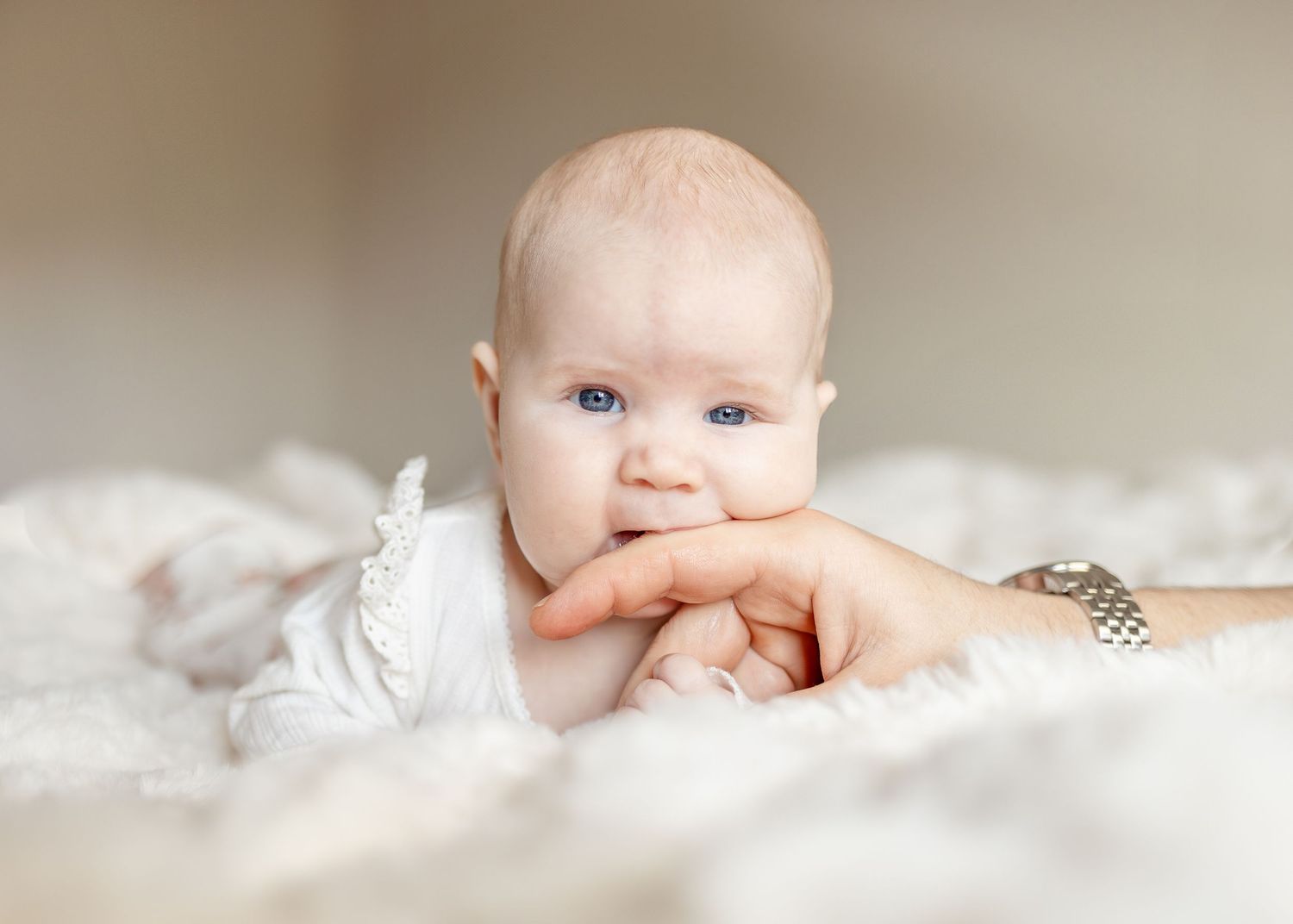 Närbild på nyfödd som ligger på vit bäddning under nyföddfotografering.