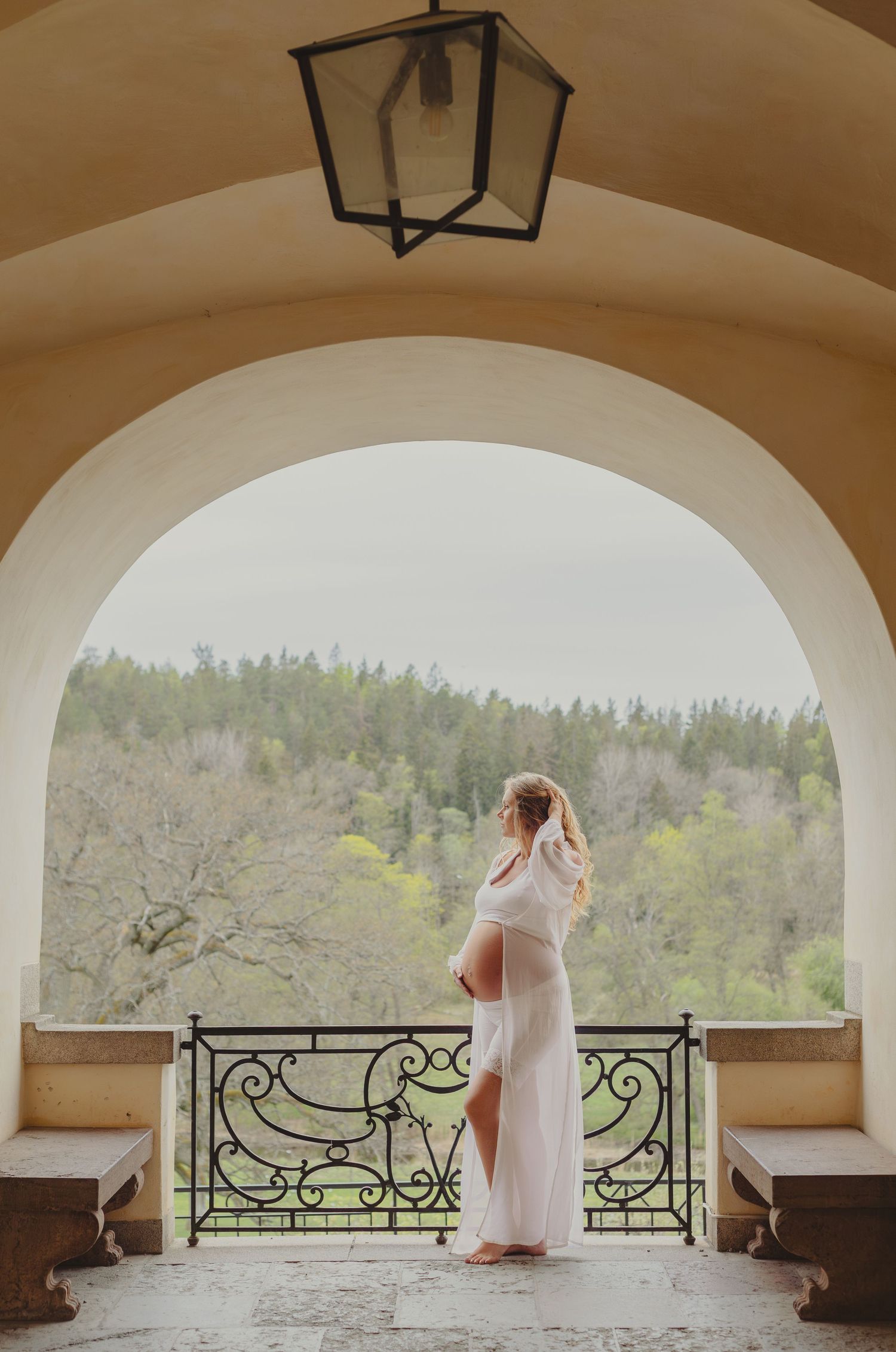 Gravid kvinna på slottsbalkong under en elegant gravidfotografering i Stockholm, fotograferad av gravidfotograf.