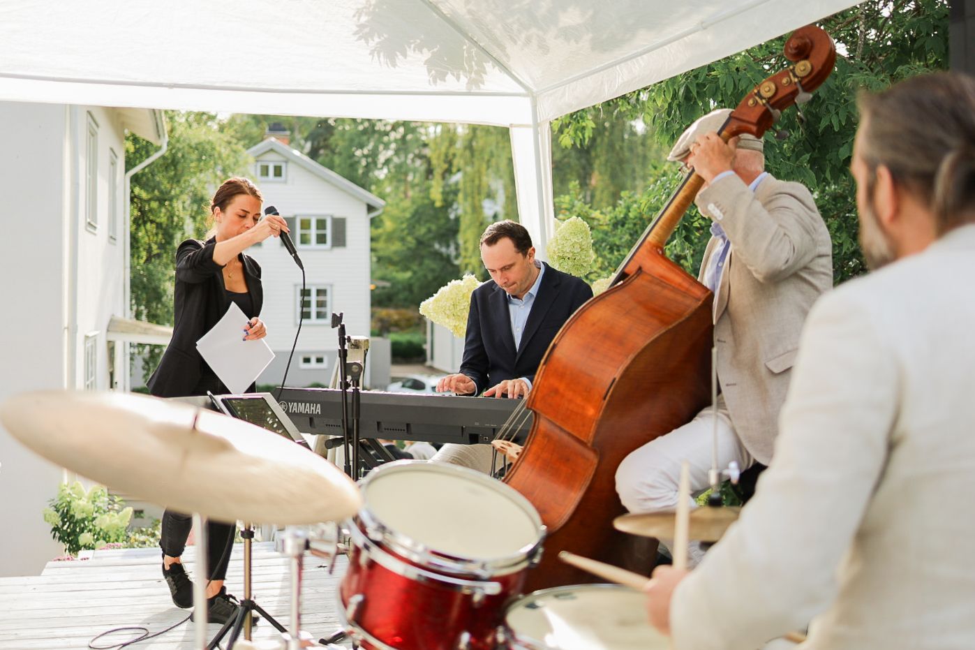 Jazzband spelar utomhus på företagsevent, eventfotograf dokumenterar live musik och mingel.