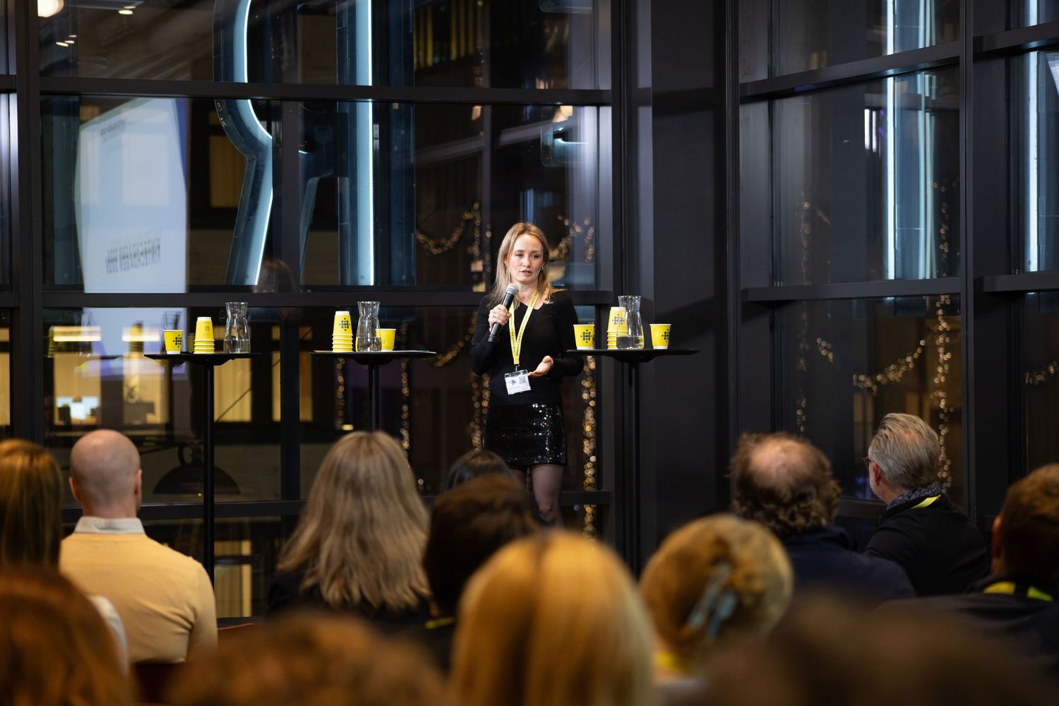 Föreläsare talar inför publik i modern konferenslokal, företagsfotograf och eventfotograf på event.