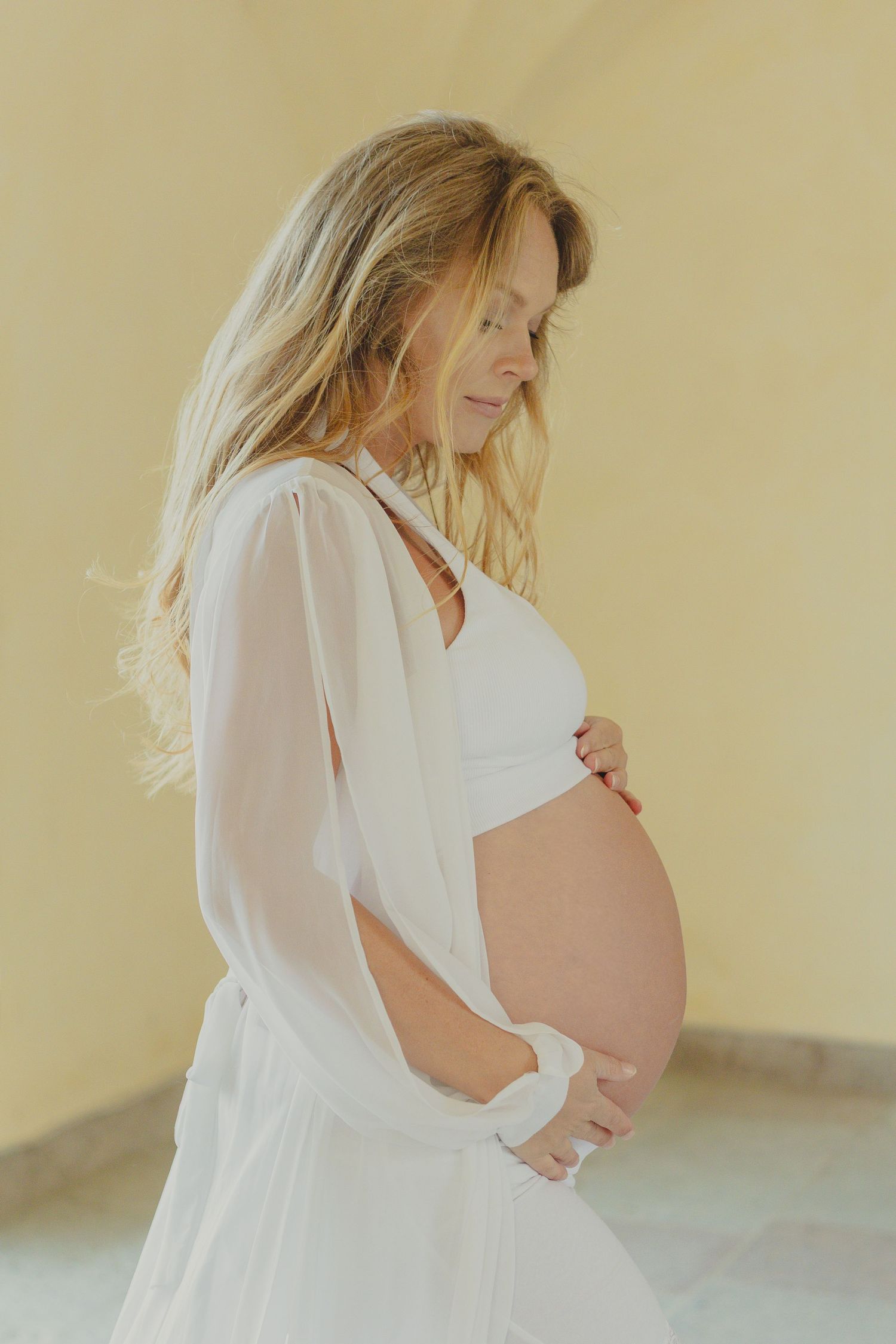 Gravid kvinna i ljus klänning under en tidlös gravidfotografering i Stockholm, fotograferad av gravidfotograf.