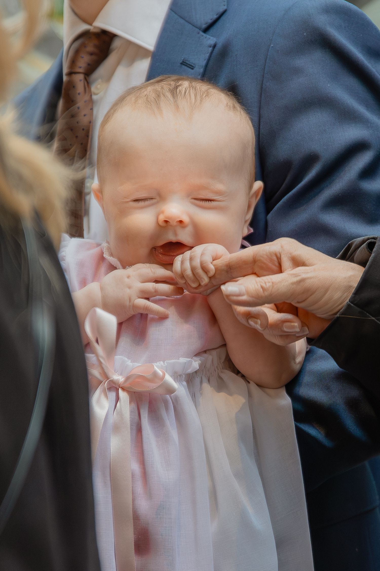 Närbild på leende bebis under dopceremoni i kyrkan, fotograferad av dopfotograf i Stockholm.