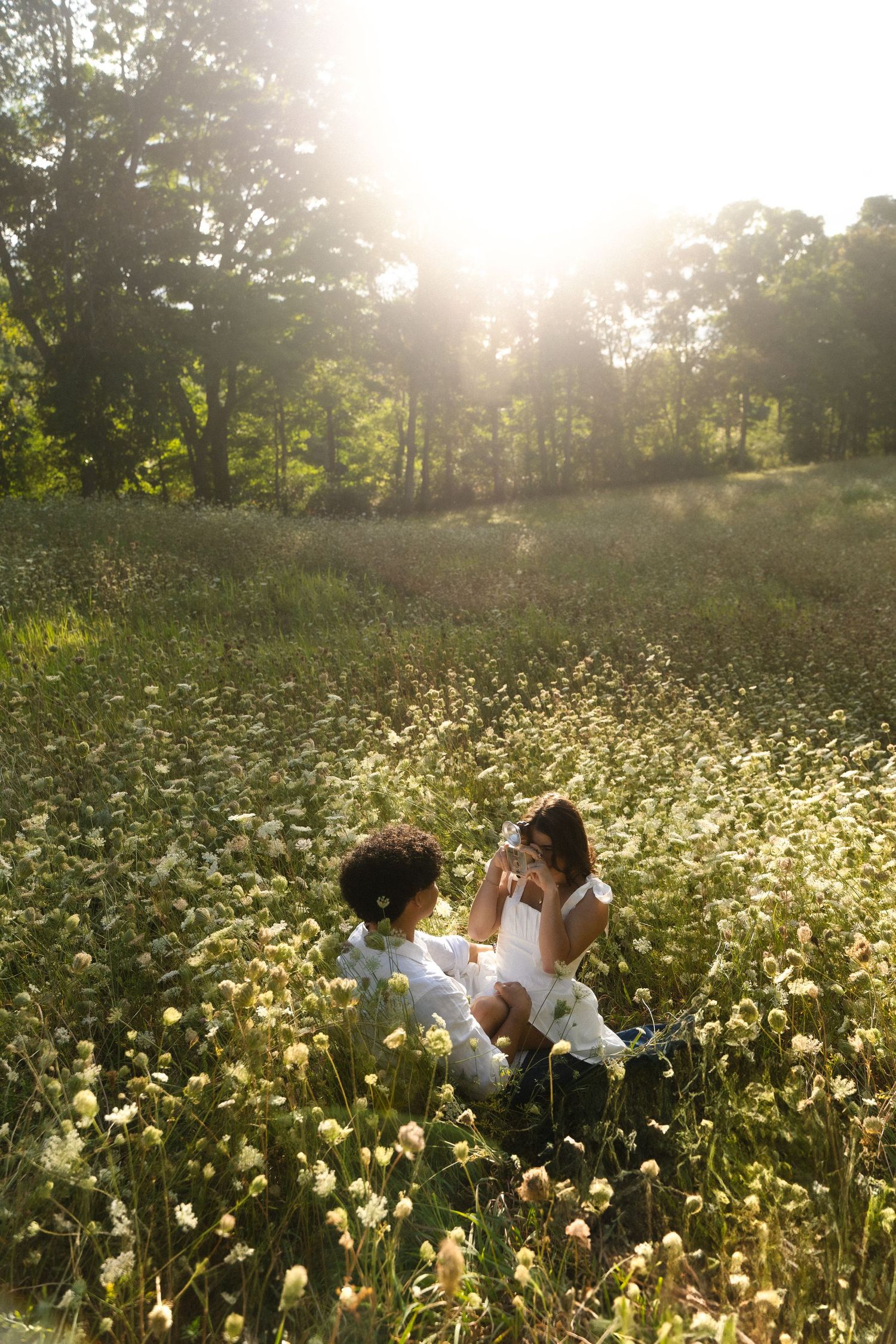 Couple lying in a field of white wildflowers during sunset.