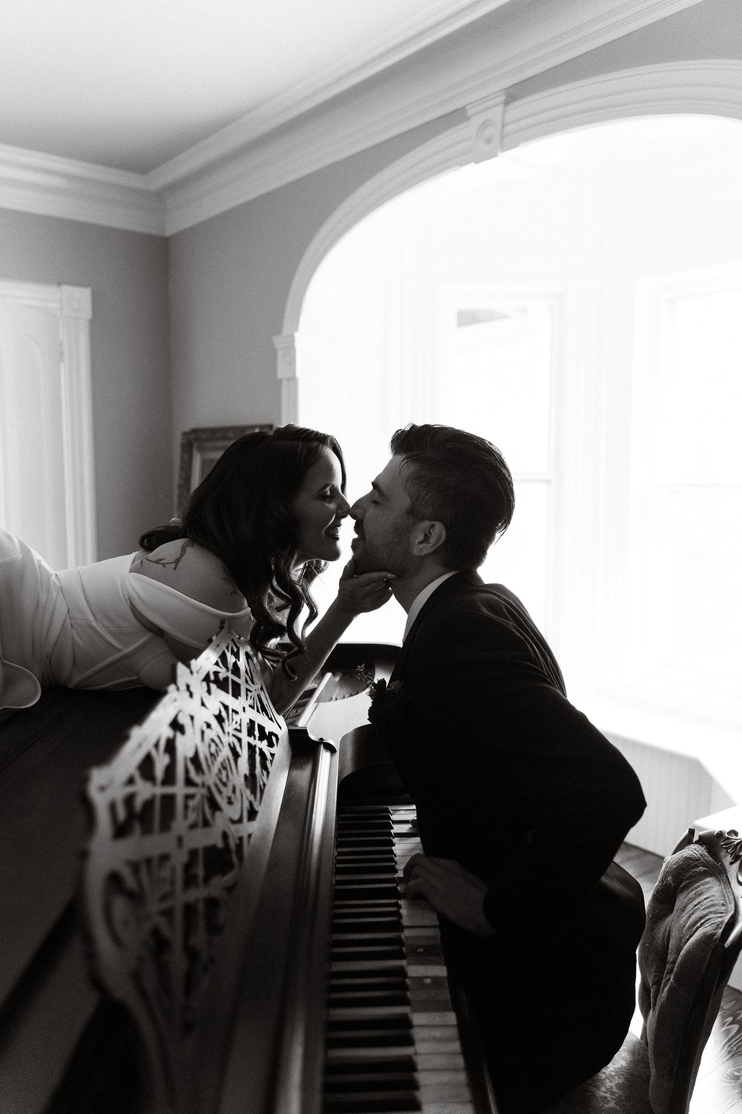 Black and white silhouette of a couple near a piano in dramatic lighting.  Rhode Island wedding venues