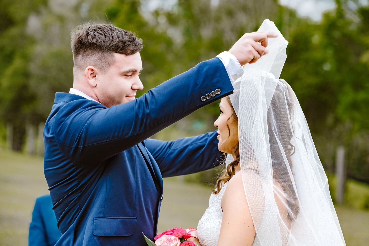 Bride and groom exchange tender kisses in lush garden setting.