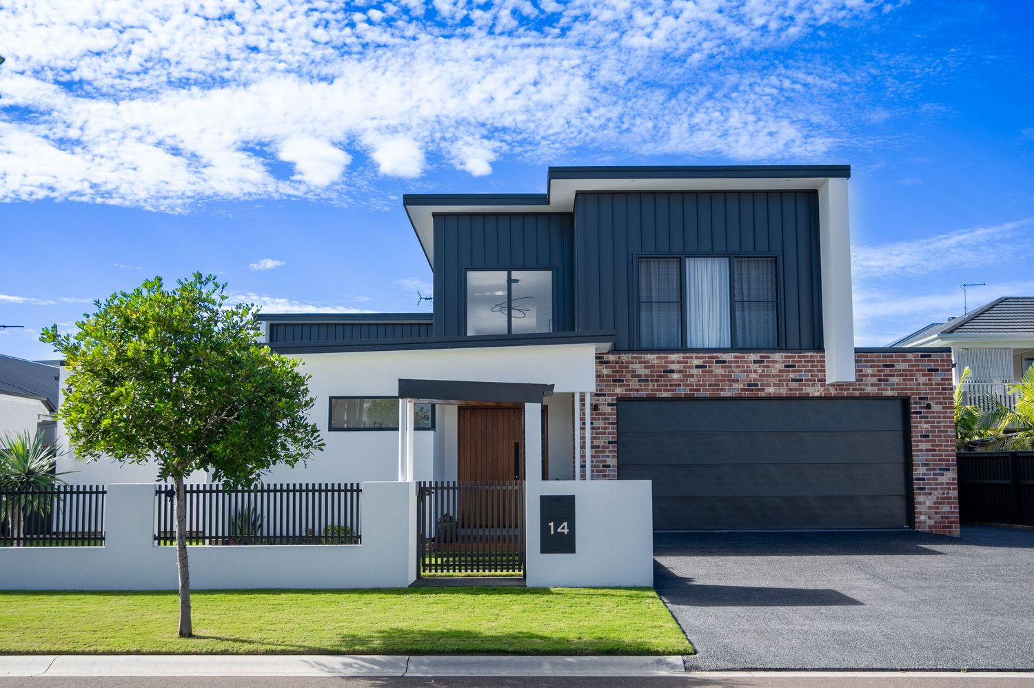 Modern minimalist house exteriors with dark and white facades under blue sky.
