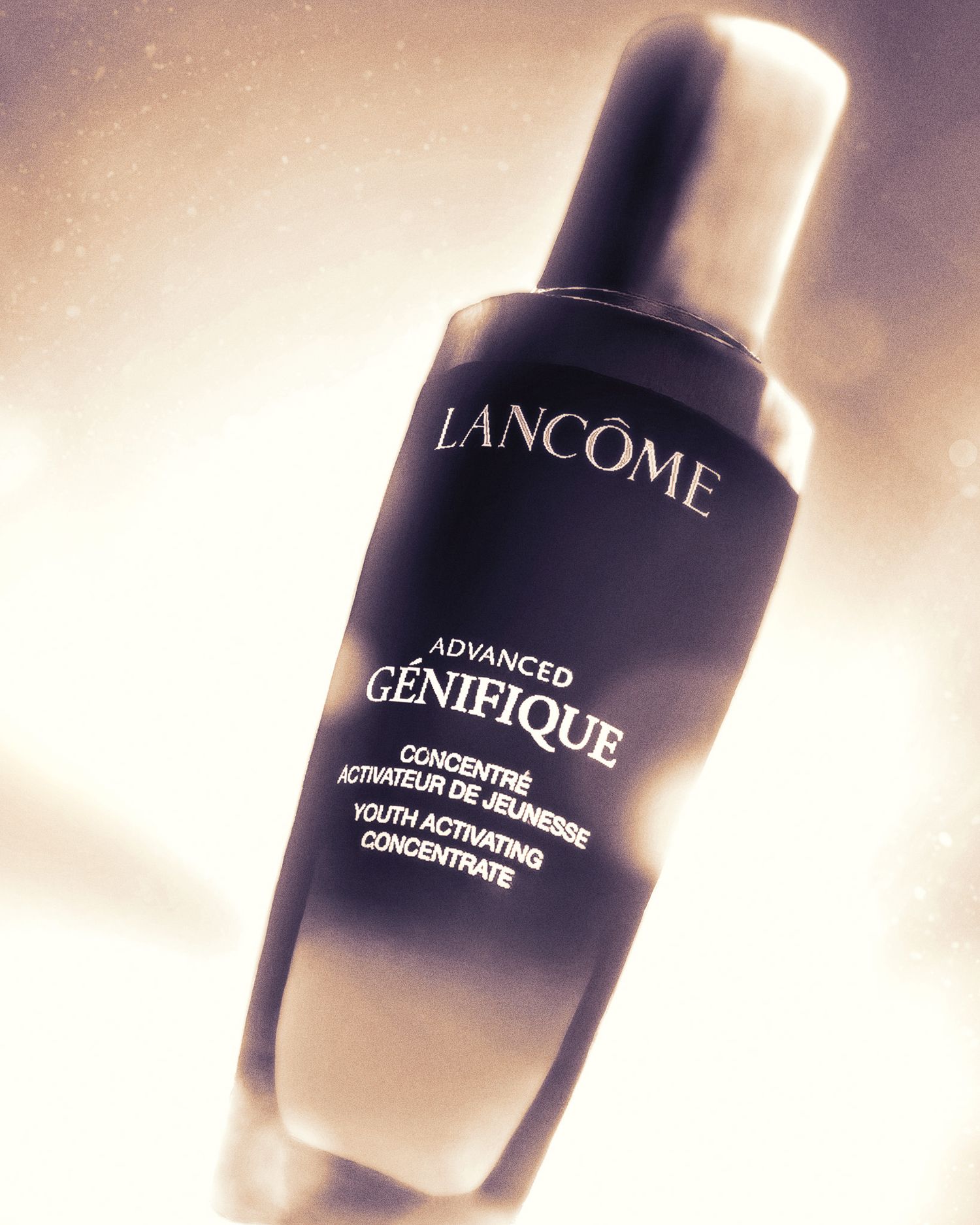 Lancome Genifique serum bottle photographed in warm dramatic lighting against light background.
