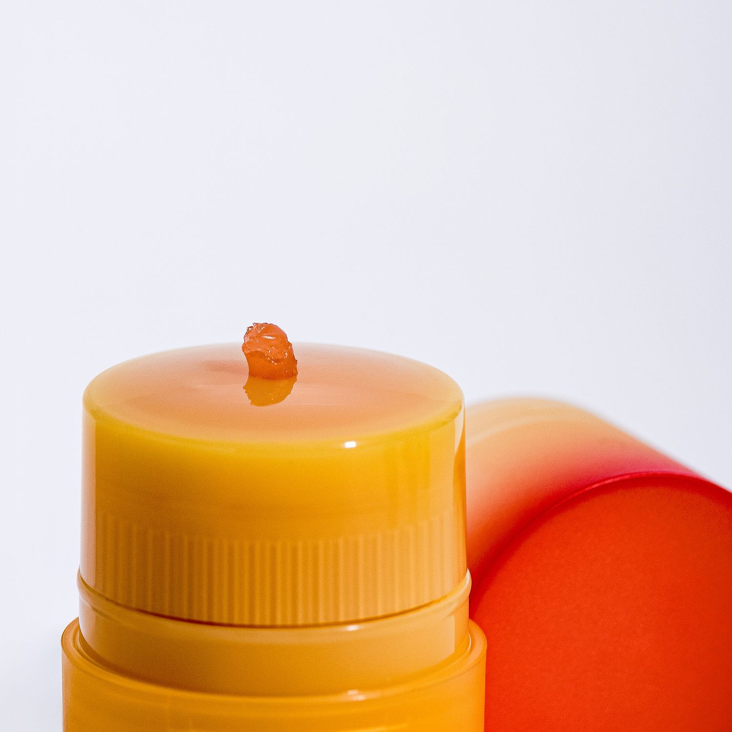 Close-up shot of two orange plastic bottles with twist caps against white background.