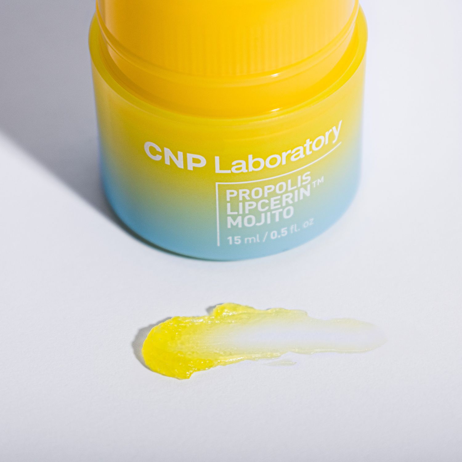 Yellow and blue gradient jar of CNP Laboratory skin care product with a small swatch of product next to it.