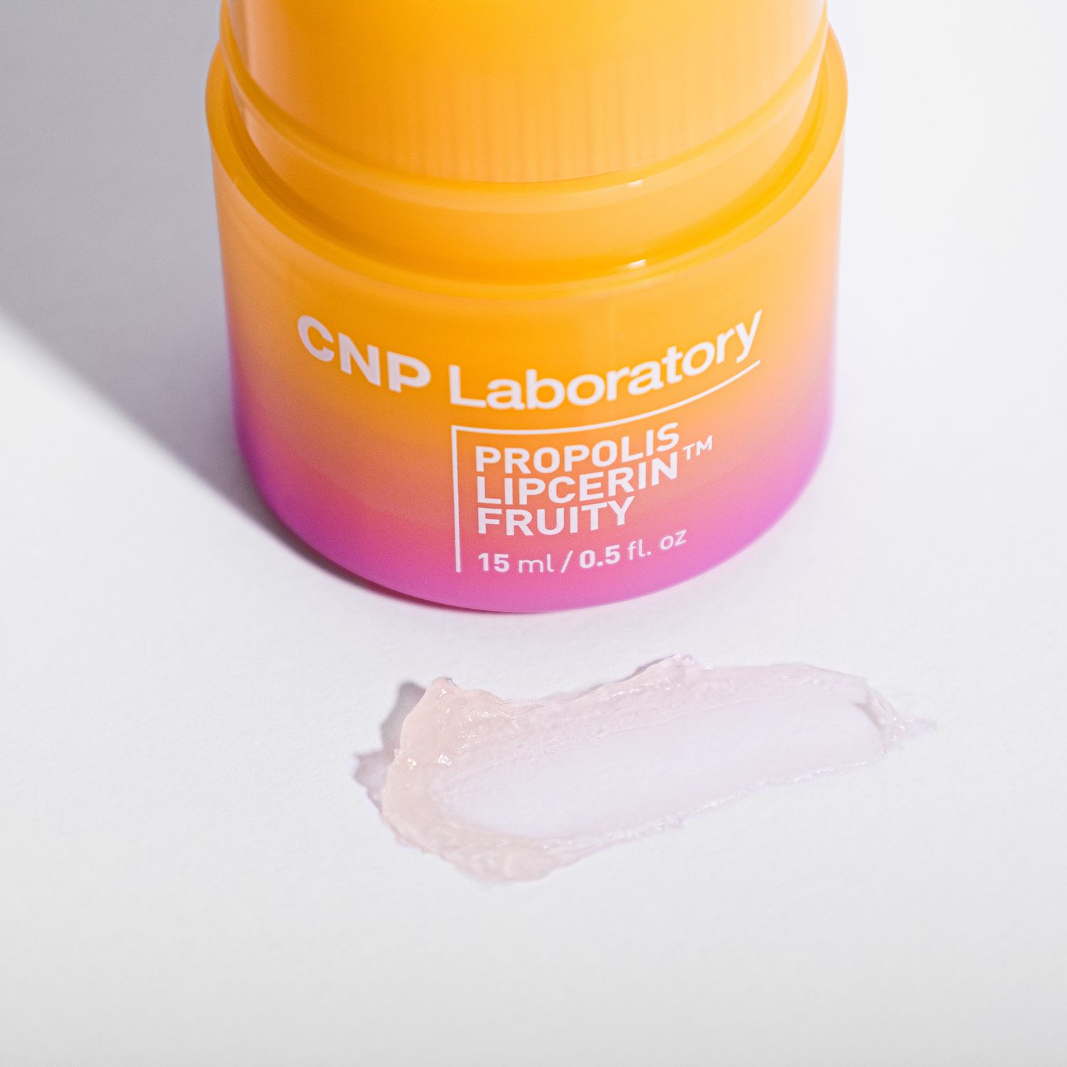 Orange and pink gradient skincare jar from CNP Laboratory with transparent skincare product sample swatched below.