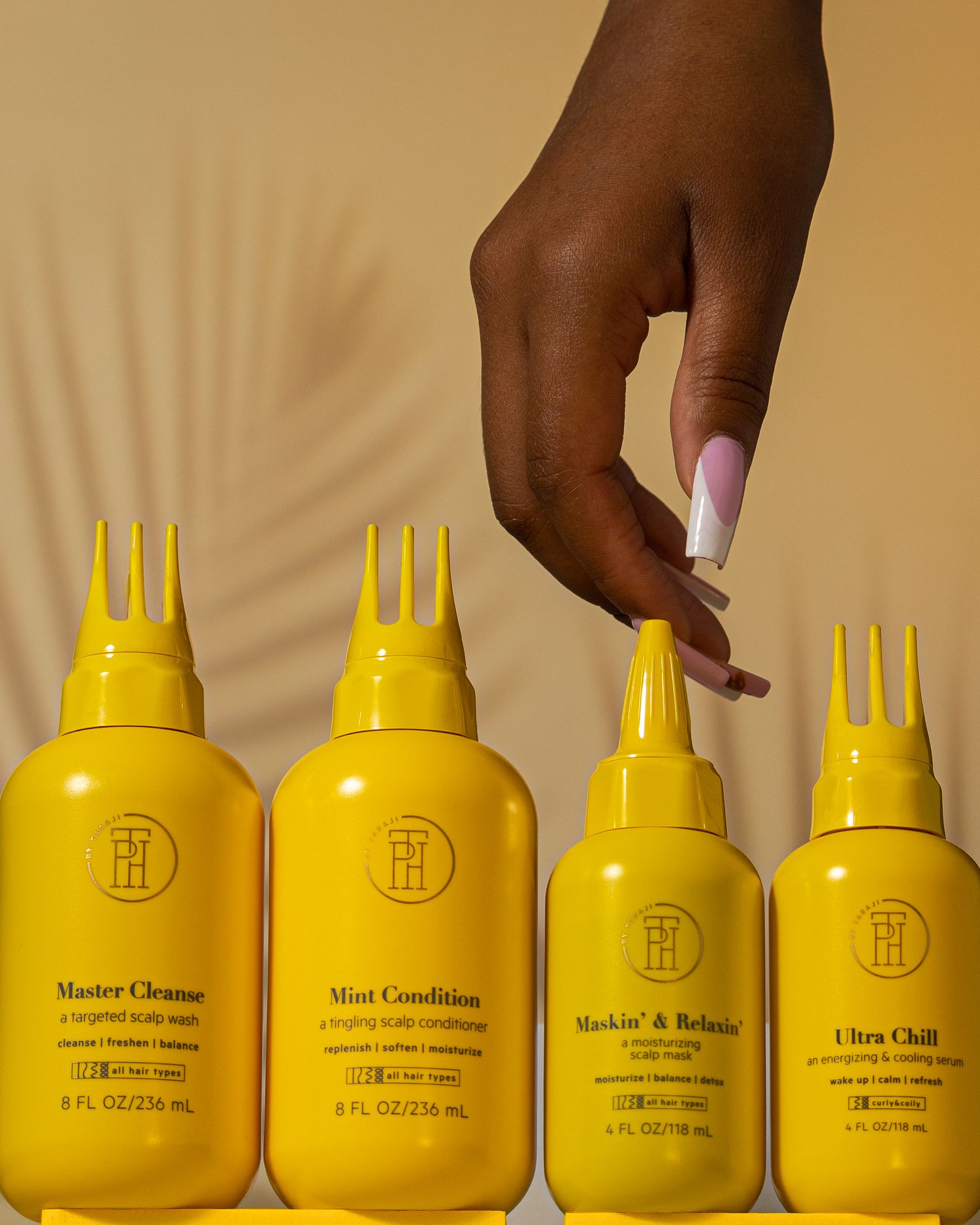 Display of four yellow hair care product bottles being shown against a neutral background.