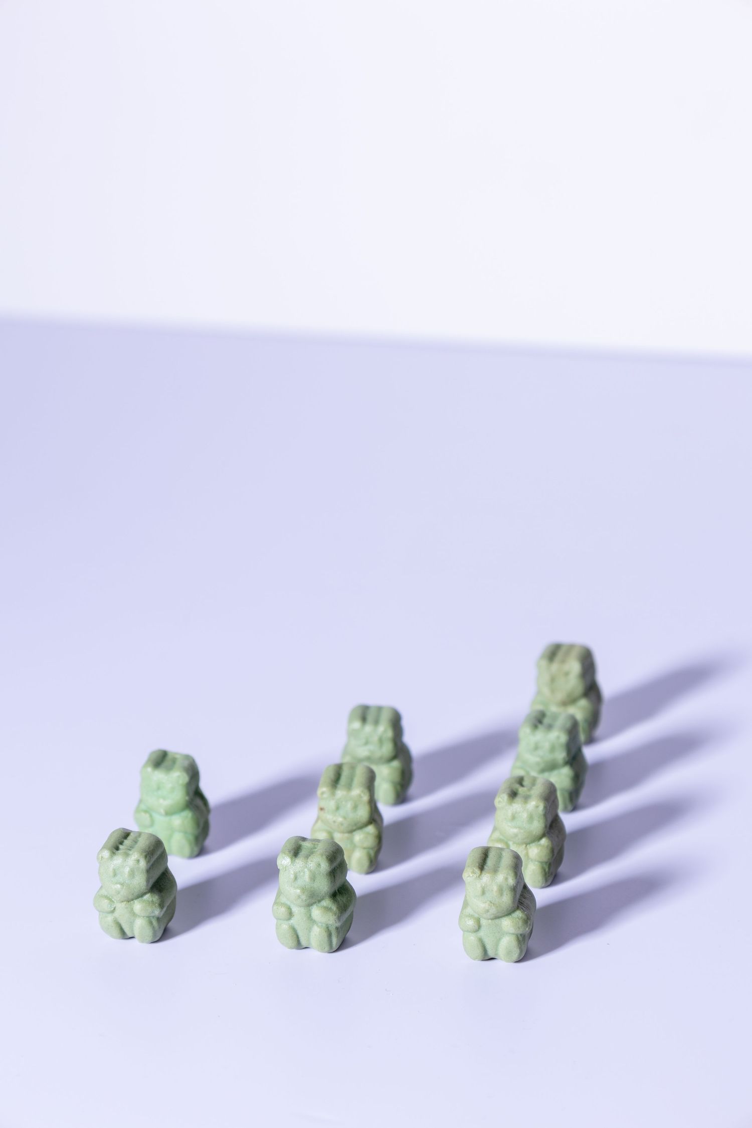 Green gummy bears arranged in neat rows on purple background.