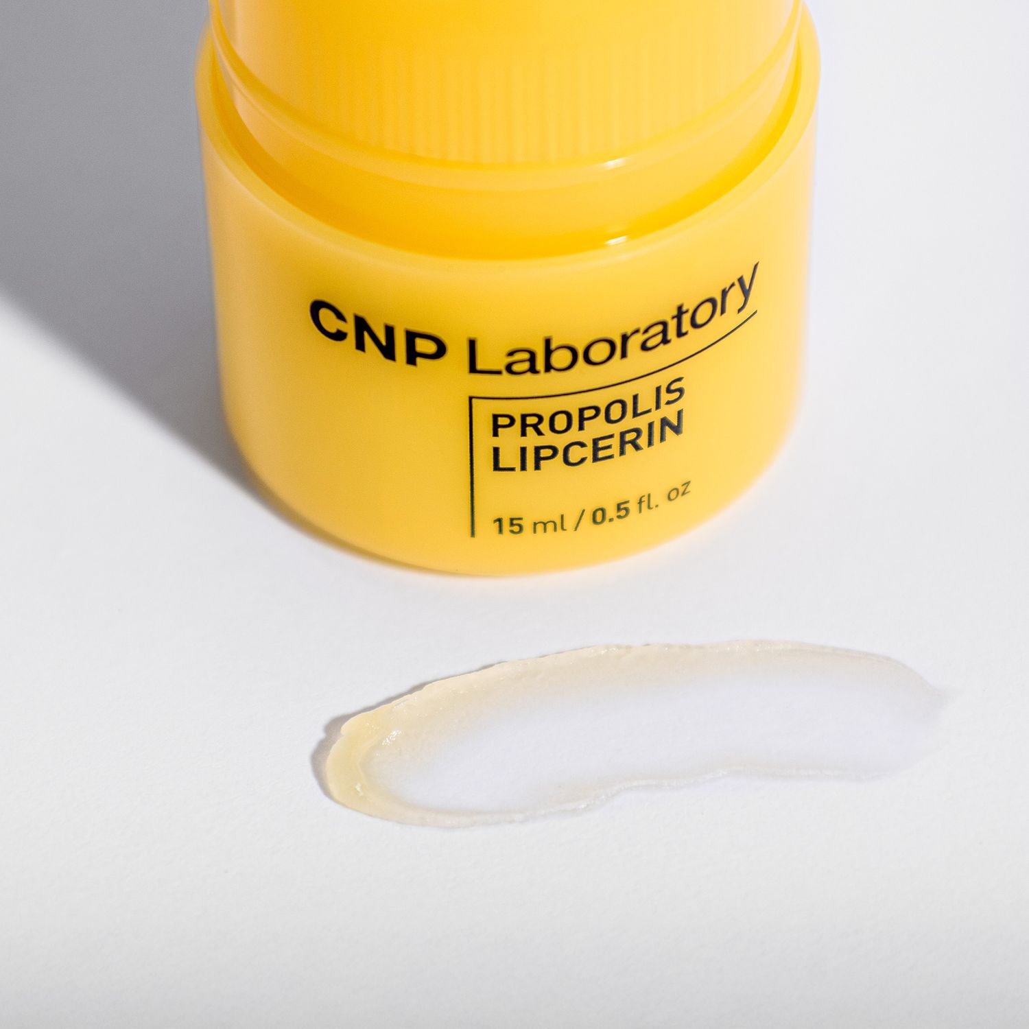 Yellow jar of CNP Laboratory Propolis Lipcerin skincare product with a small swatch of clear gel texture beside it.