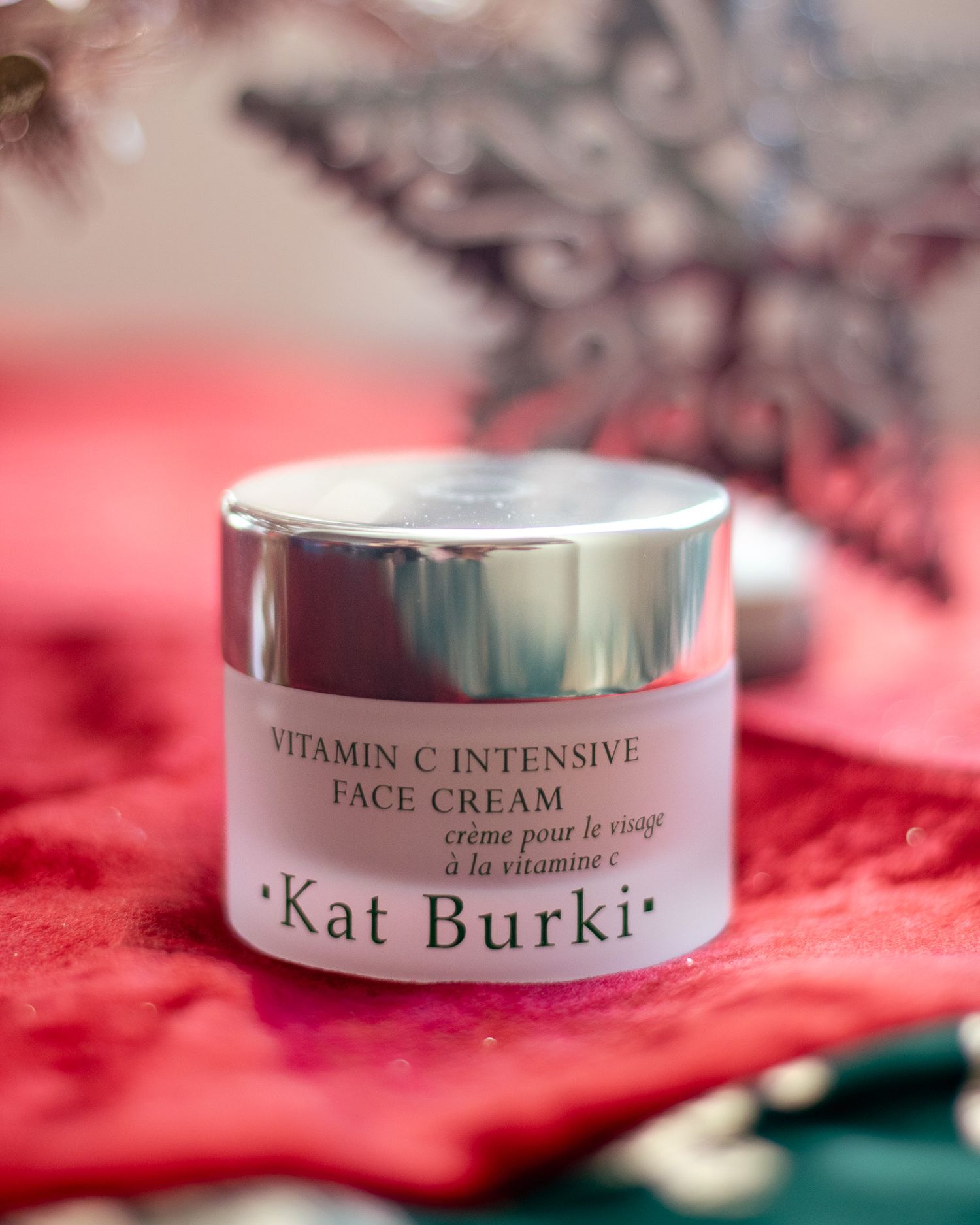 Kat Burki Vitamin C Intensive Face Cream jar on red textured background.