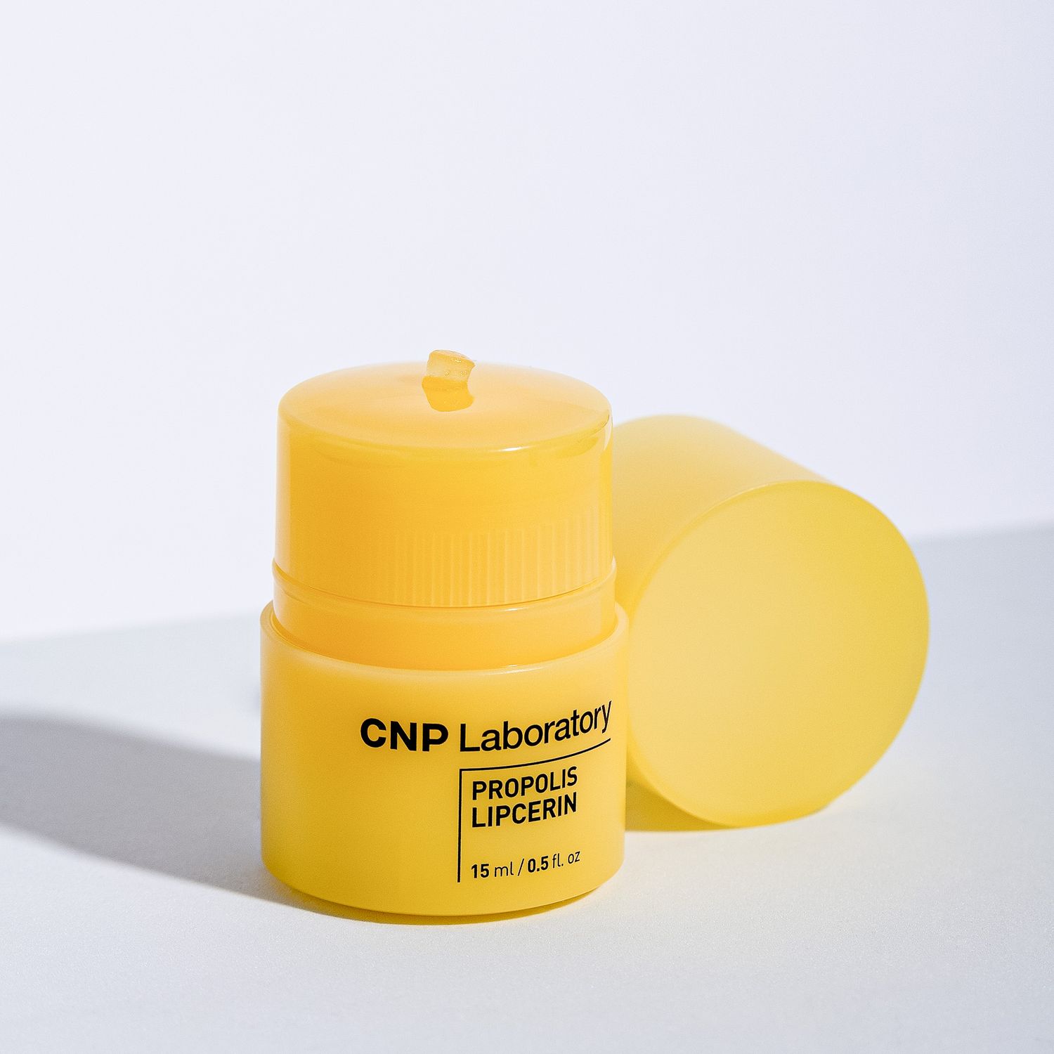 A yellow skincare product container from CNP Laboratory casting a soft shadow on a white background.