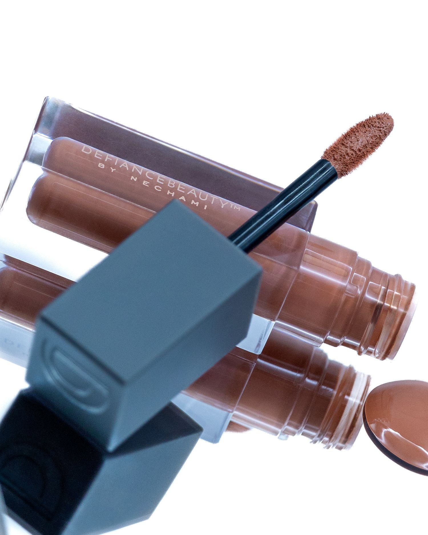 Luxury nude brown liquid lipstick with applicator wand on reflective surface.
