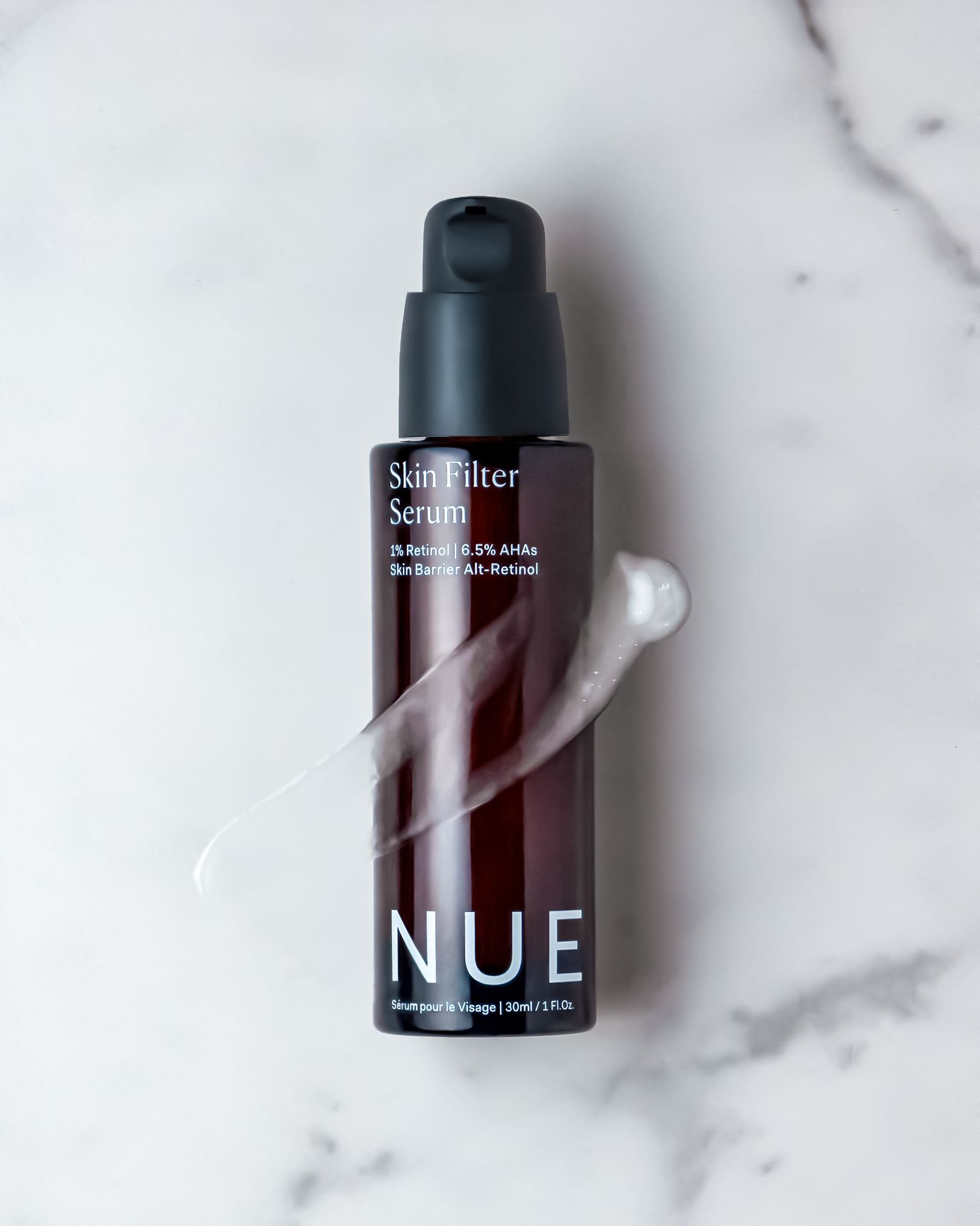 NUE Sun Filter Serum with white product swipe on marble background.