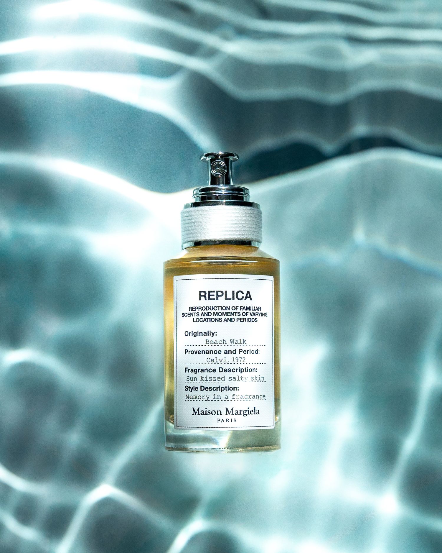 Maison Margiela Replica perfume bottle floating in rippling turquoise water.