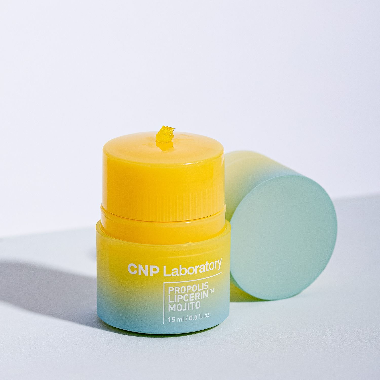 Yellow skincare product container with blue text labeled 'CNP Laboratory' next to a pastel green cylinder on white background.