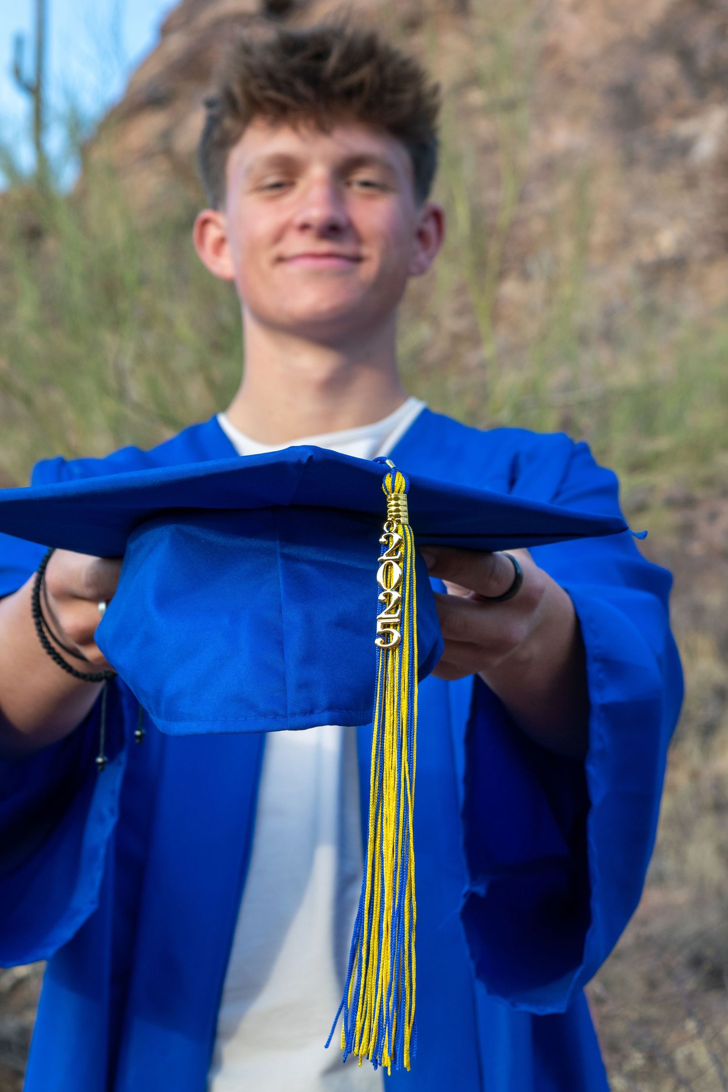 A photo of a graduate proudly holding his cap and tassel out for the camera to see