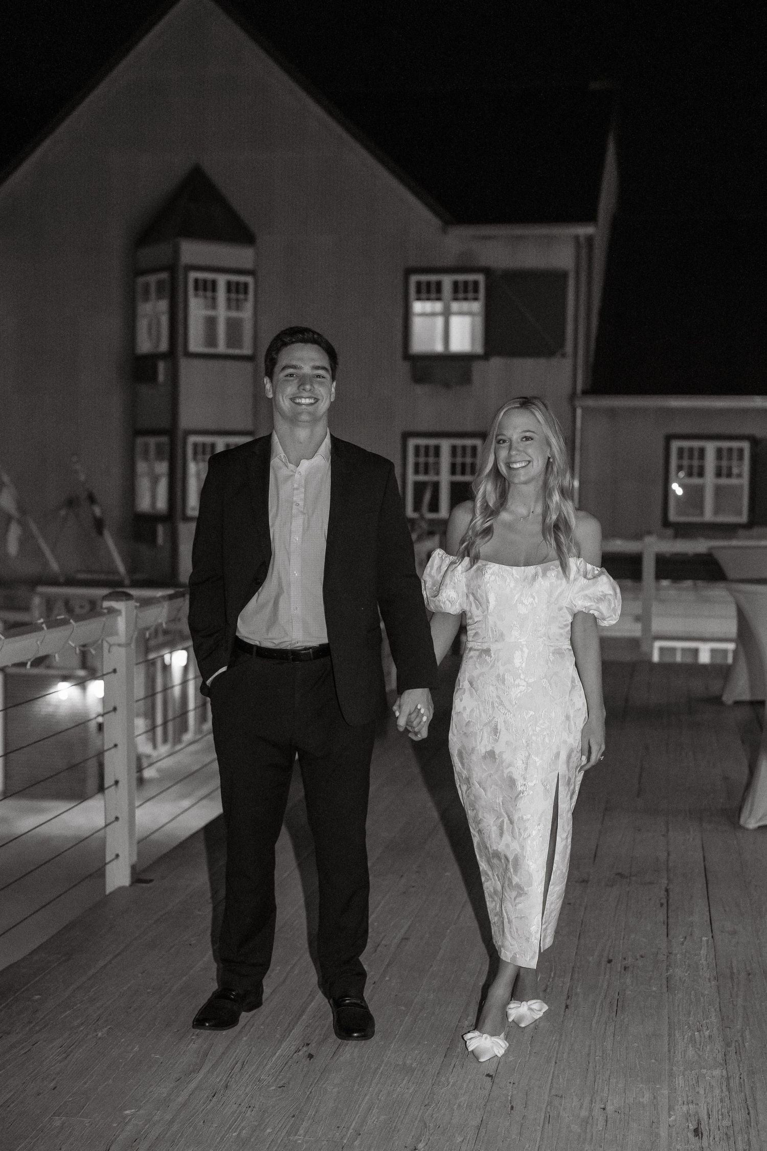 Black and white nighttime sequence of couple walking together on wooden dock.