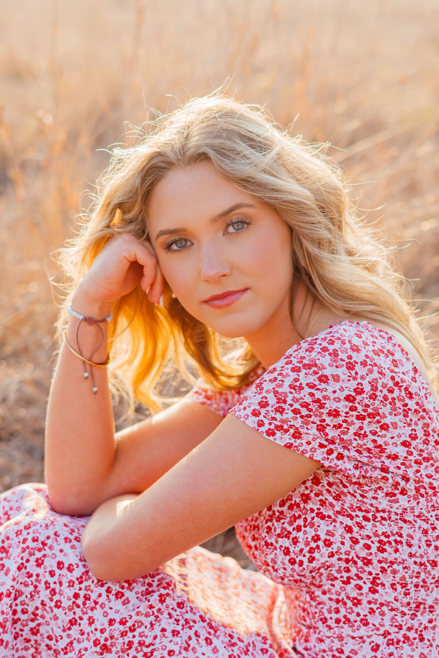 Lifestyle portrait featuring a floral print red dress and golden sunset lighting.