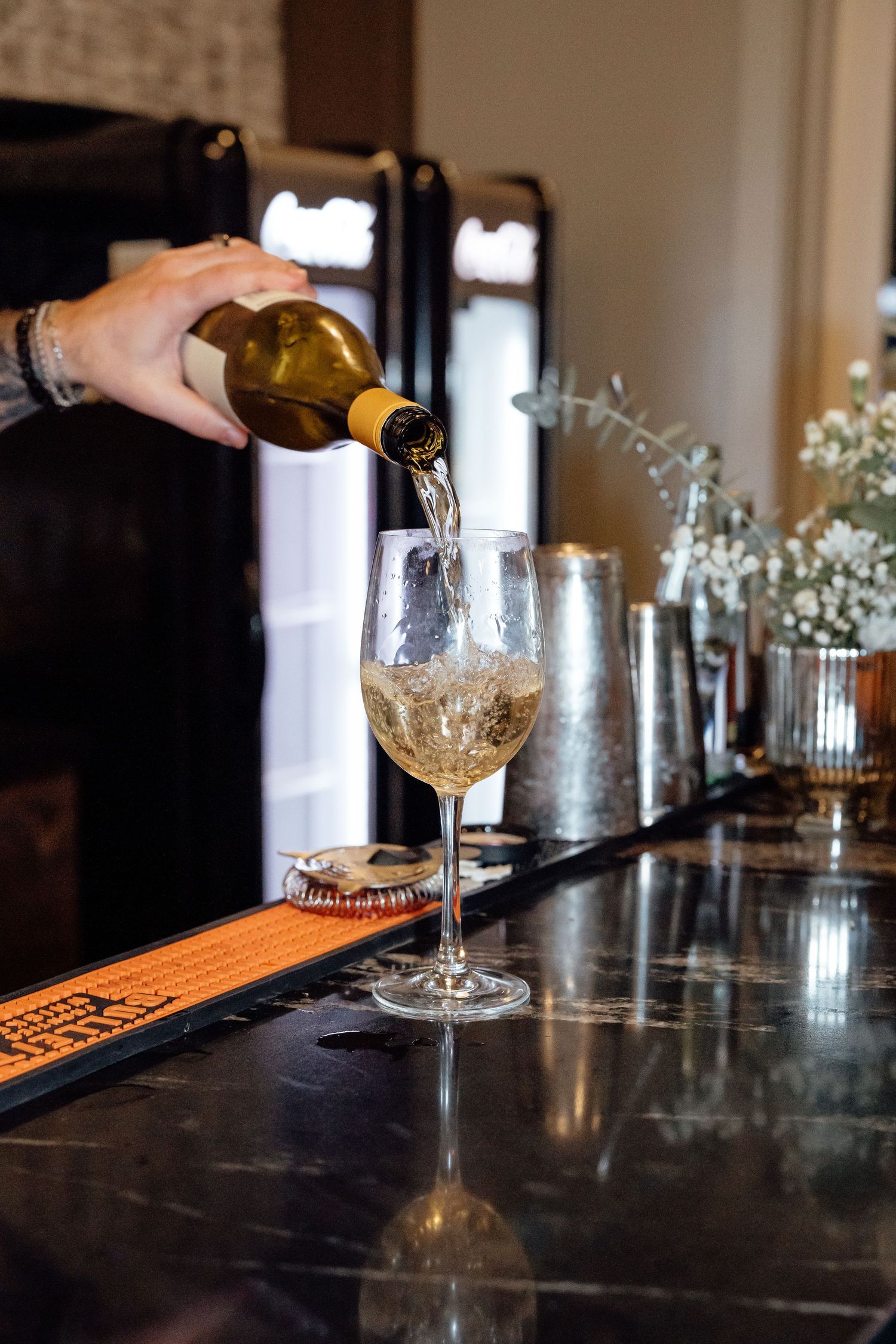 Wine being poured into glasses at an elegant bar setting with baby's breath flowers.