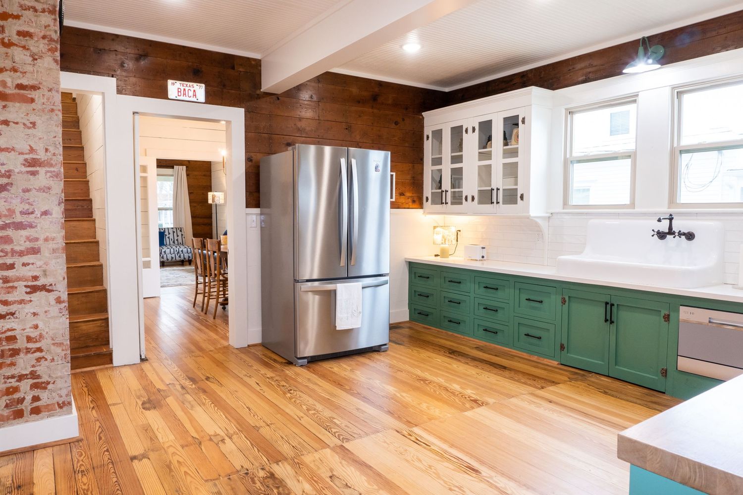 Modern kitchen interior with hardwood floors and green cabinets.