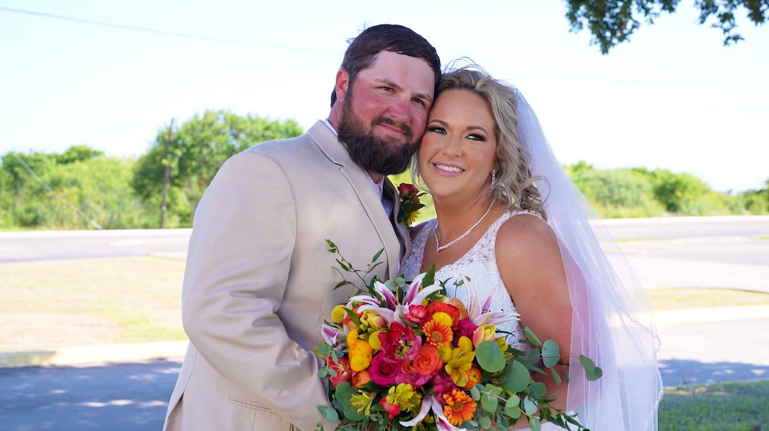Bride and groom share joyful moments outdoors with vibrant orange and red floral arrangements.