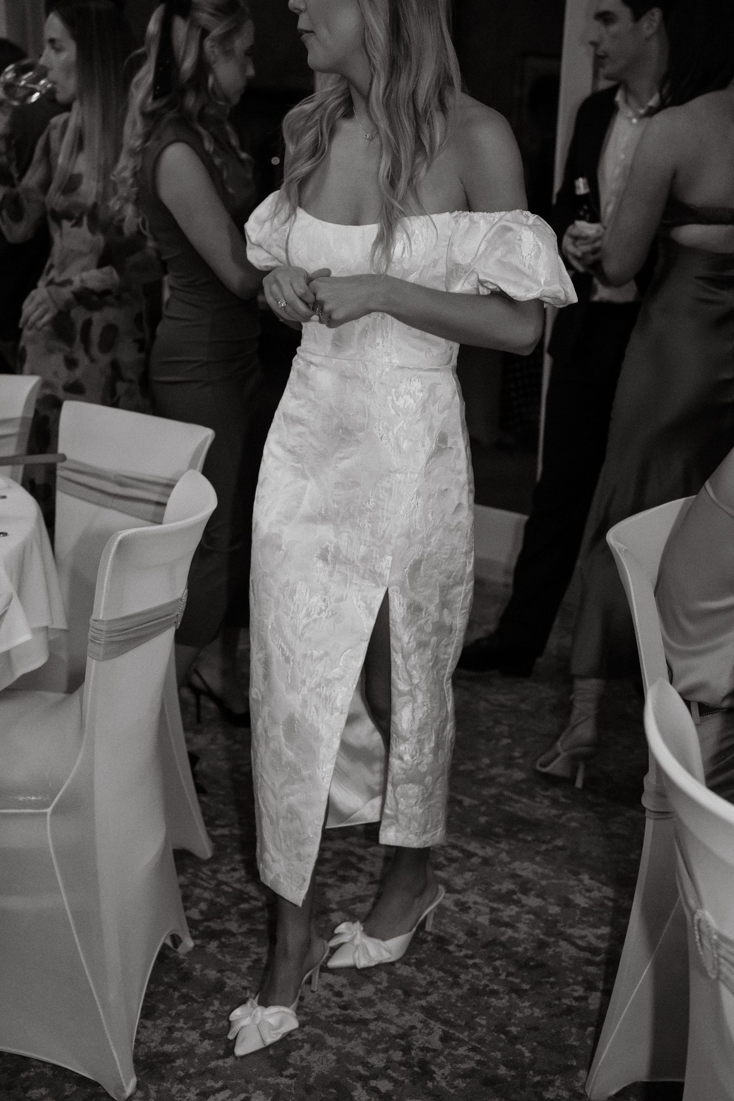 Party guests in formal attire mingle and dance at an evening reception.