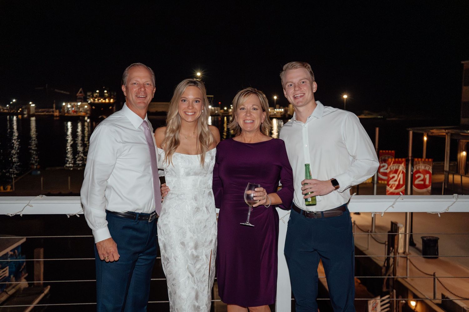 People celebrating at a waterfront venue during an evening party with drinks and festive attire.