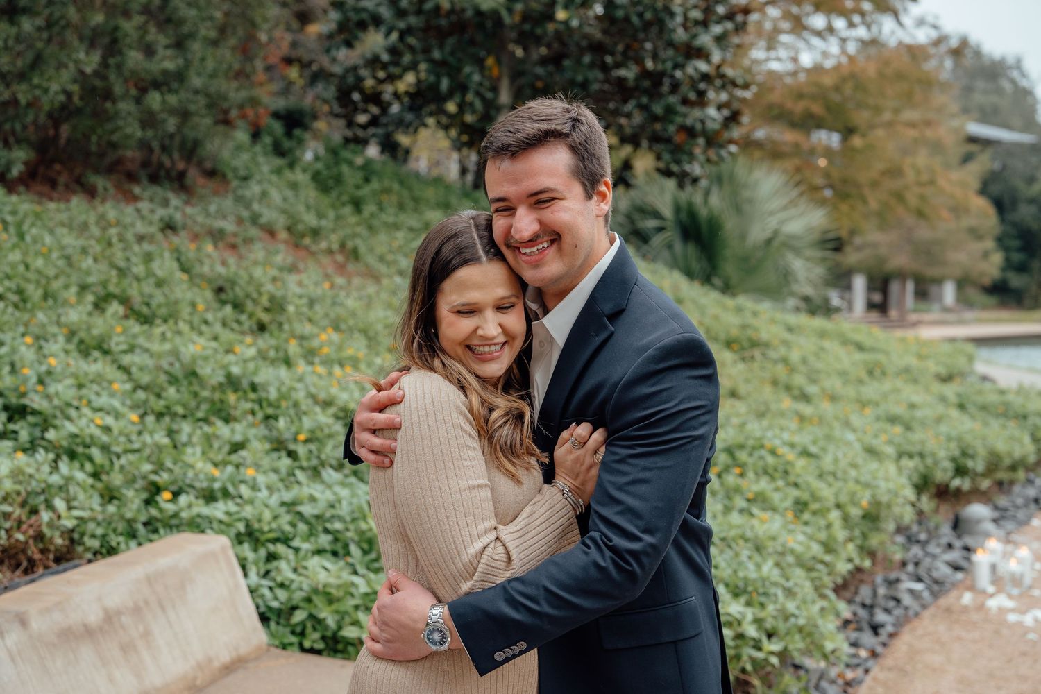A couple shares a loving moment on a path surrounded by greenery.