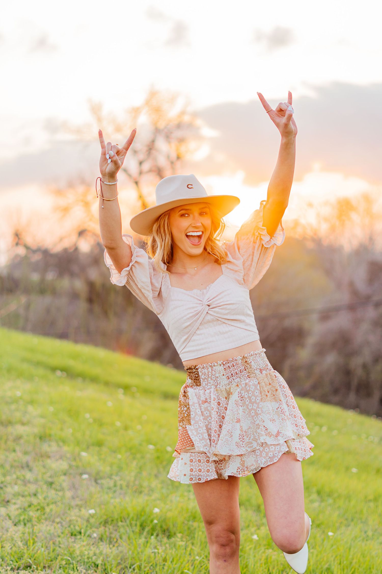 Dancing freely in white clothing and boots on a hillside during golden hour.