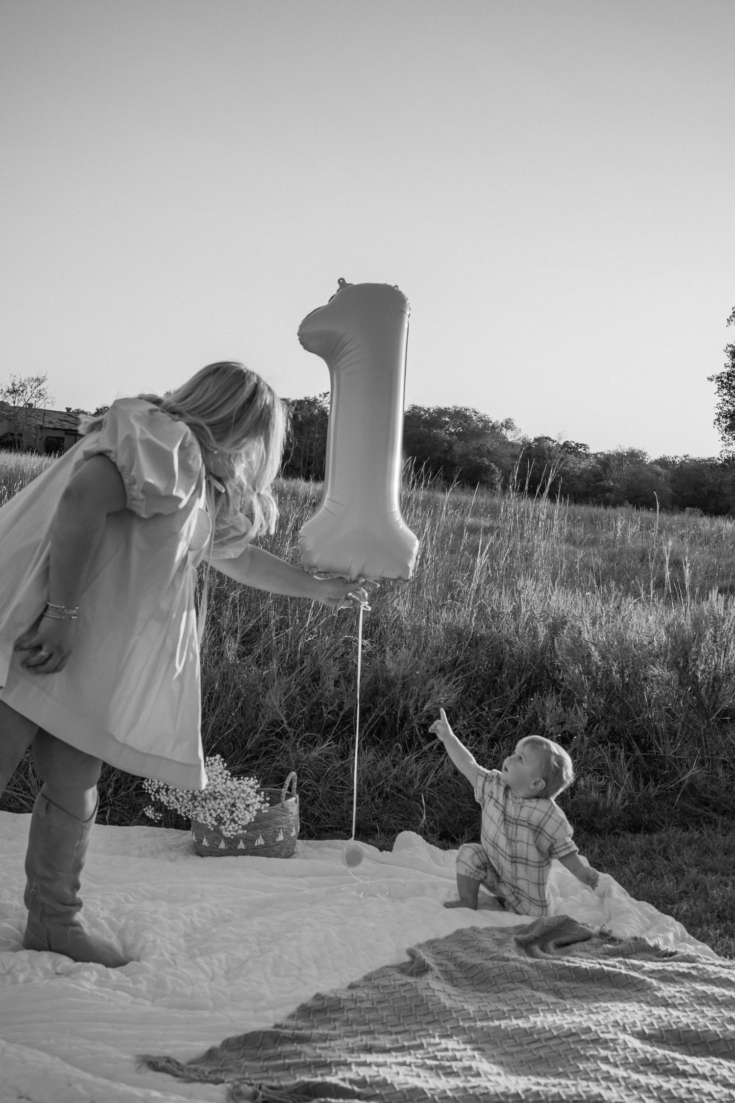 Black and white photo series of family playing on picnic blanket outdoors.