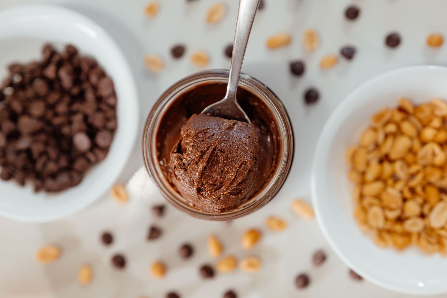 Various chocolate chips and nuts displayed in white bowls.