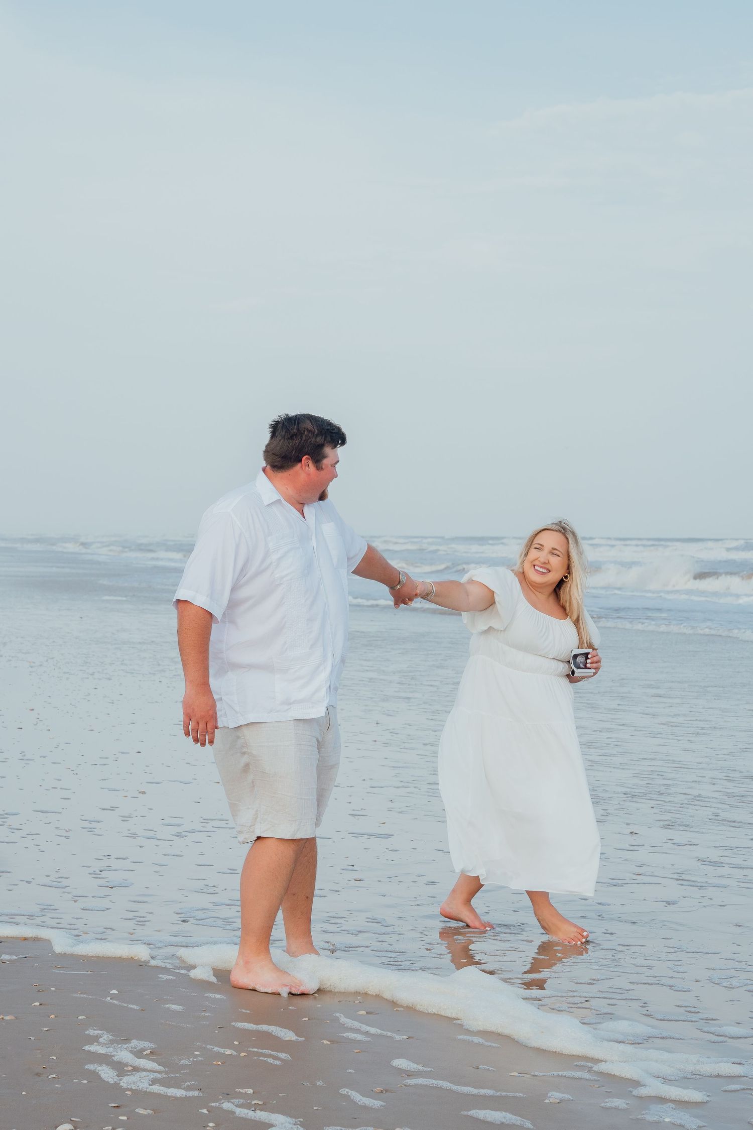 Romantic beach photography sequence showing couple in white outfits playing in the surf.