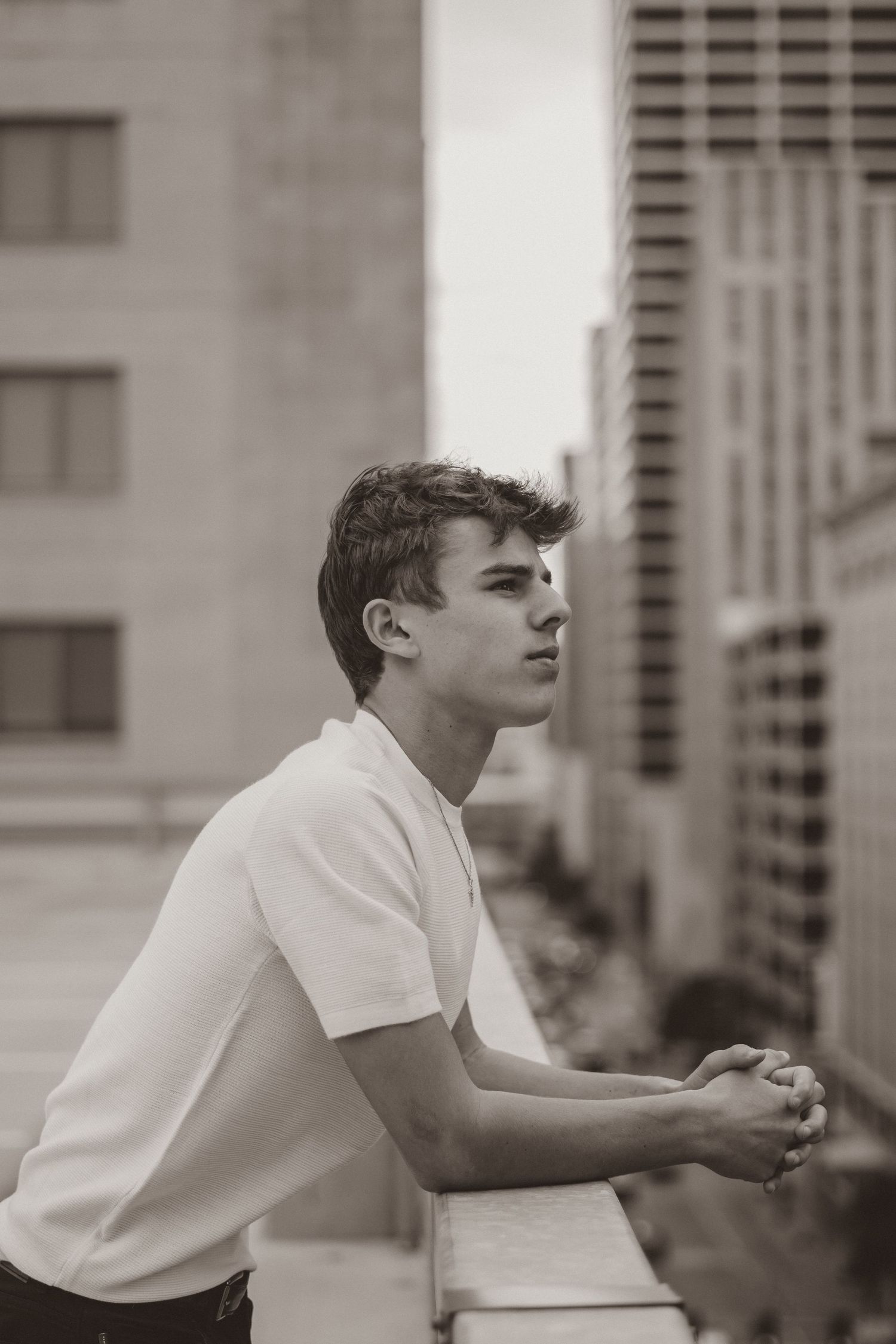 Black and white urban portrait of person in white t-shirt looking contemplative.