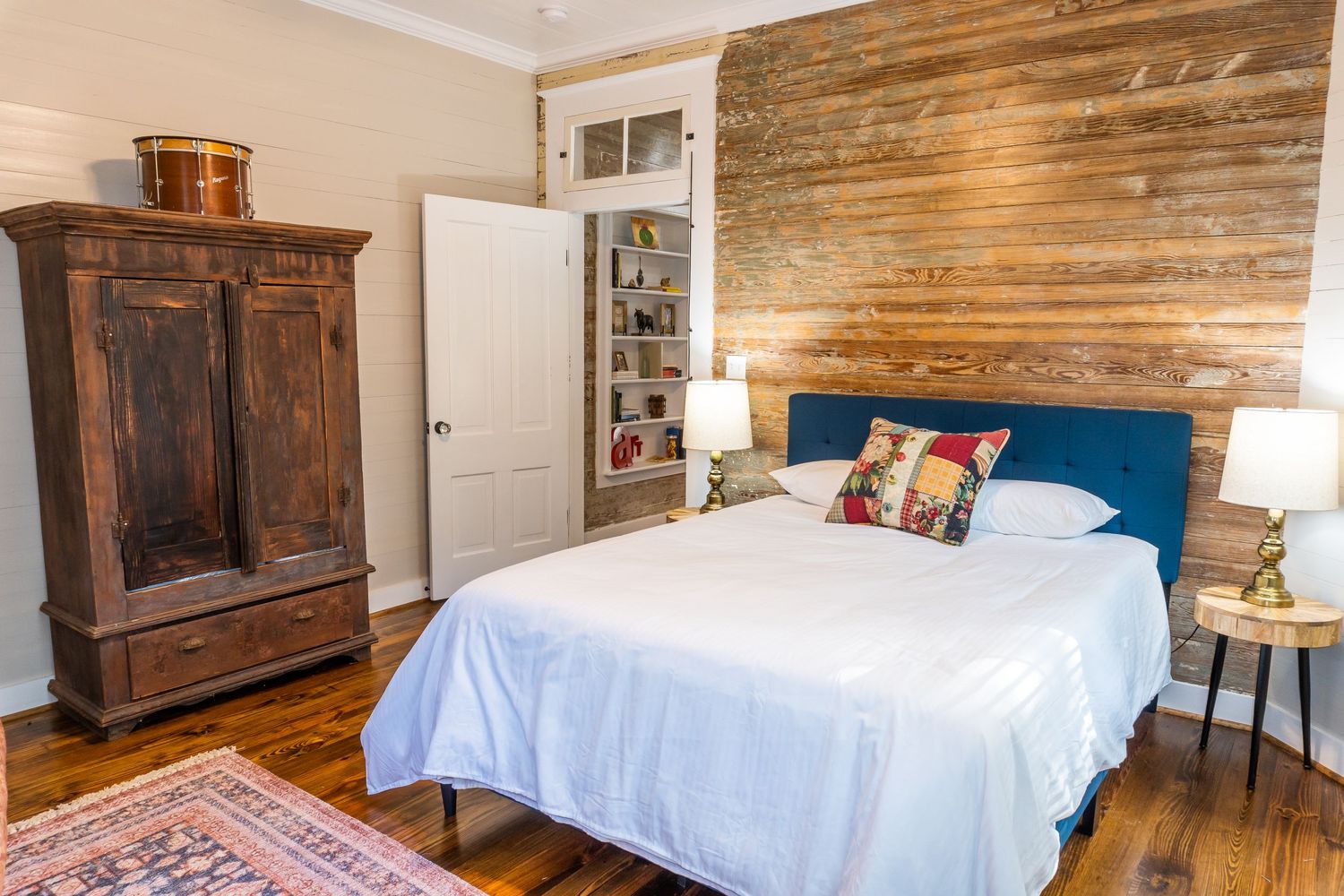 Rustic bedroom interior with wooden walls and white bedding in a cozy setting.