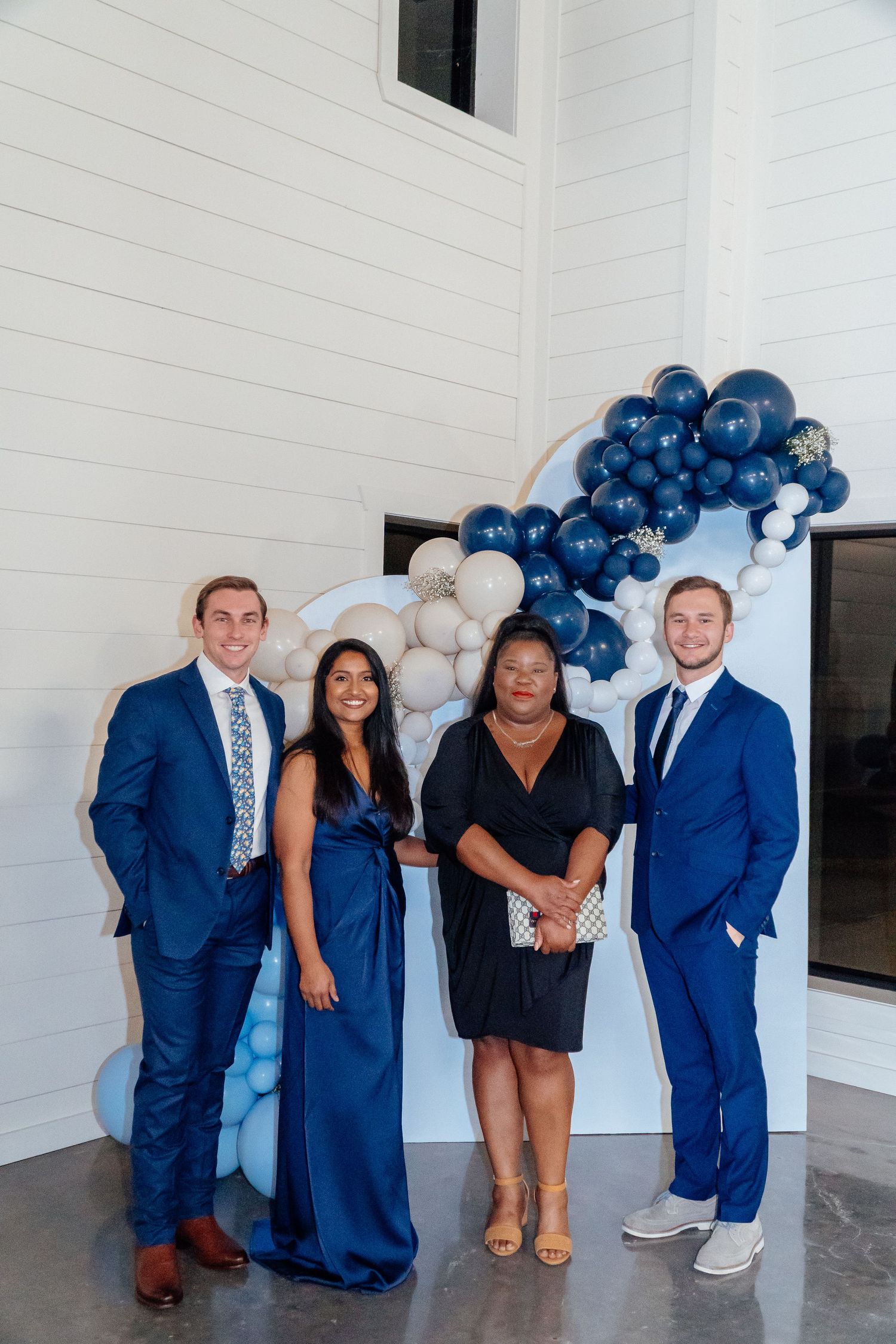 Group photo with people in formal attire against balloon backdrop.