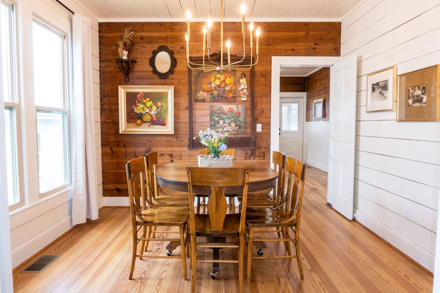 Long wooden dining room with white walls and rustic decor featuring multiple seating areas.