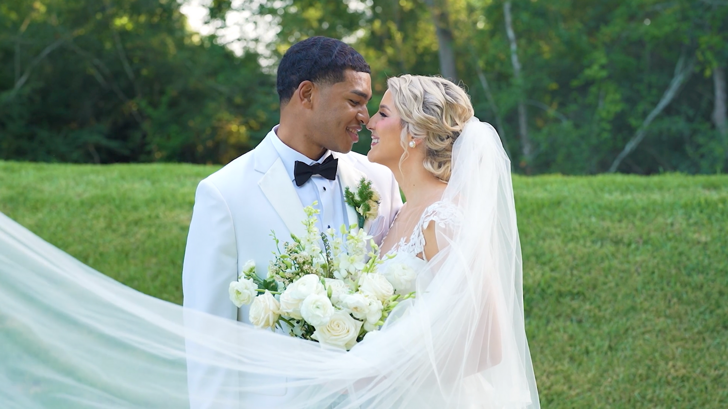 Newlyweds share a joyful moment in a lush outdoor garden setting.
